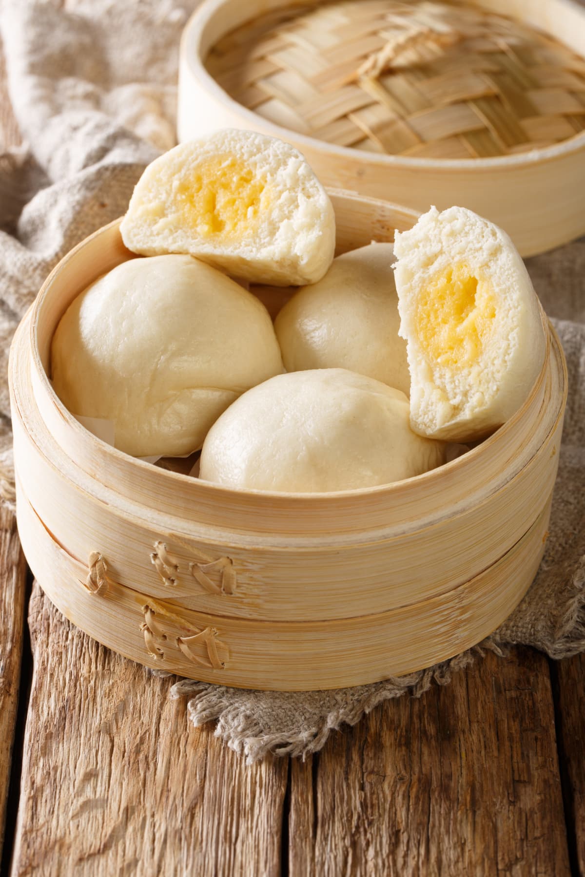 Liu Sha Bao, Salted Egg Yolk Custard Streamed Bun close-up on the table. vertical