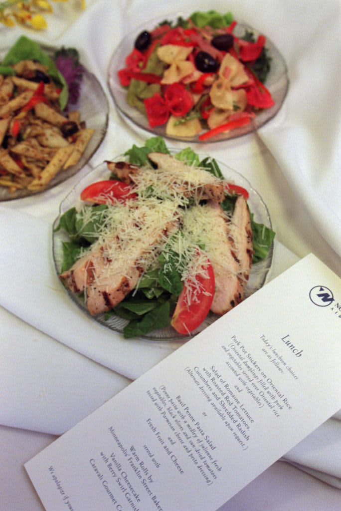 Various salads served on an airplane next to a printed menu