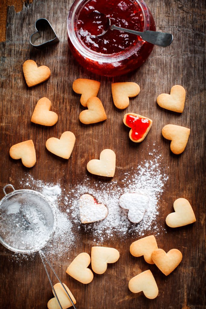 Heart shaped sugar cookies with jam on a wooden table