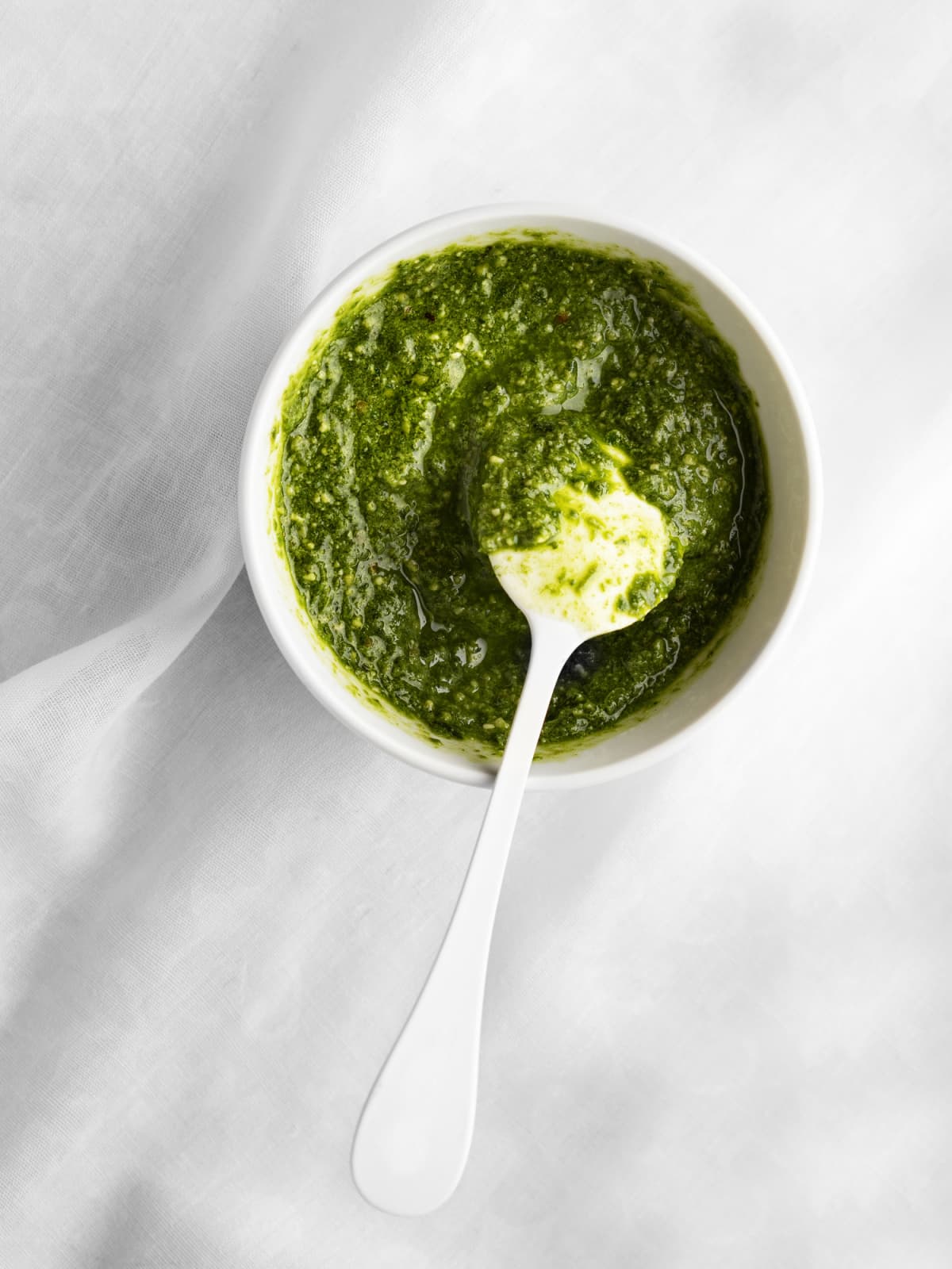 A bowl of pesto sauce with spoon
