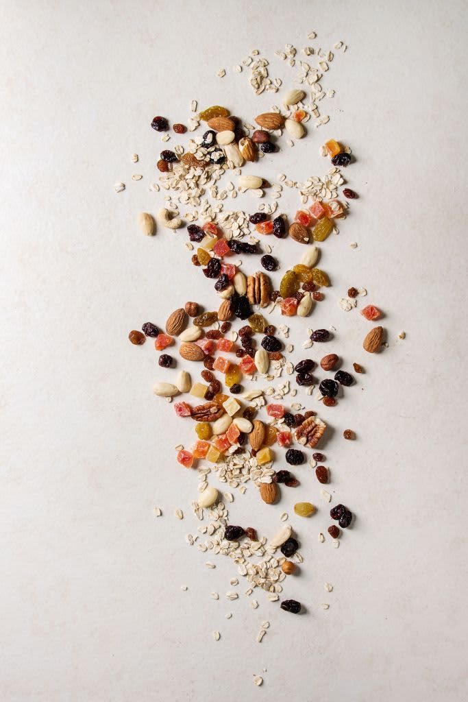 Variety of dried fruits. nuts and oat flakes for cooking homemade healthy breakfast muesli or granola energy bars over white texture background. Flat lay. space. . (Photo by: Natasha Breen/REDA&CO/Universal Images Group via Getty Images)