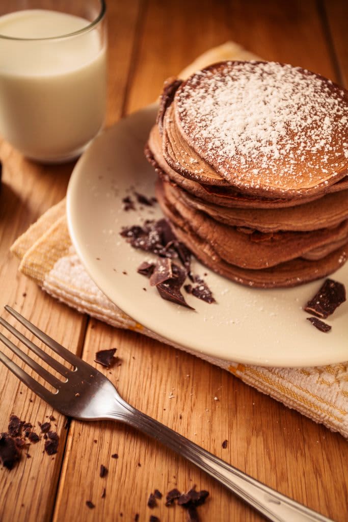 A view of delicious cocoa pancakes with dark chocolate and powdered sugar on a wooden table. (Photo by: Daniele Orsi/REDA&CO/Universal Images Group via Getty Images)