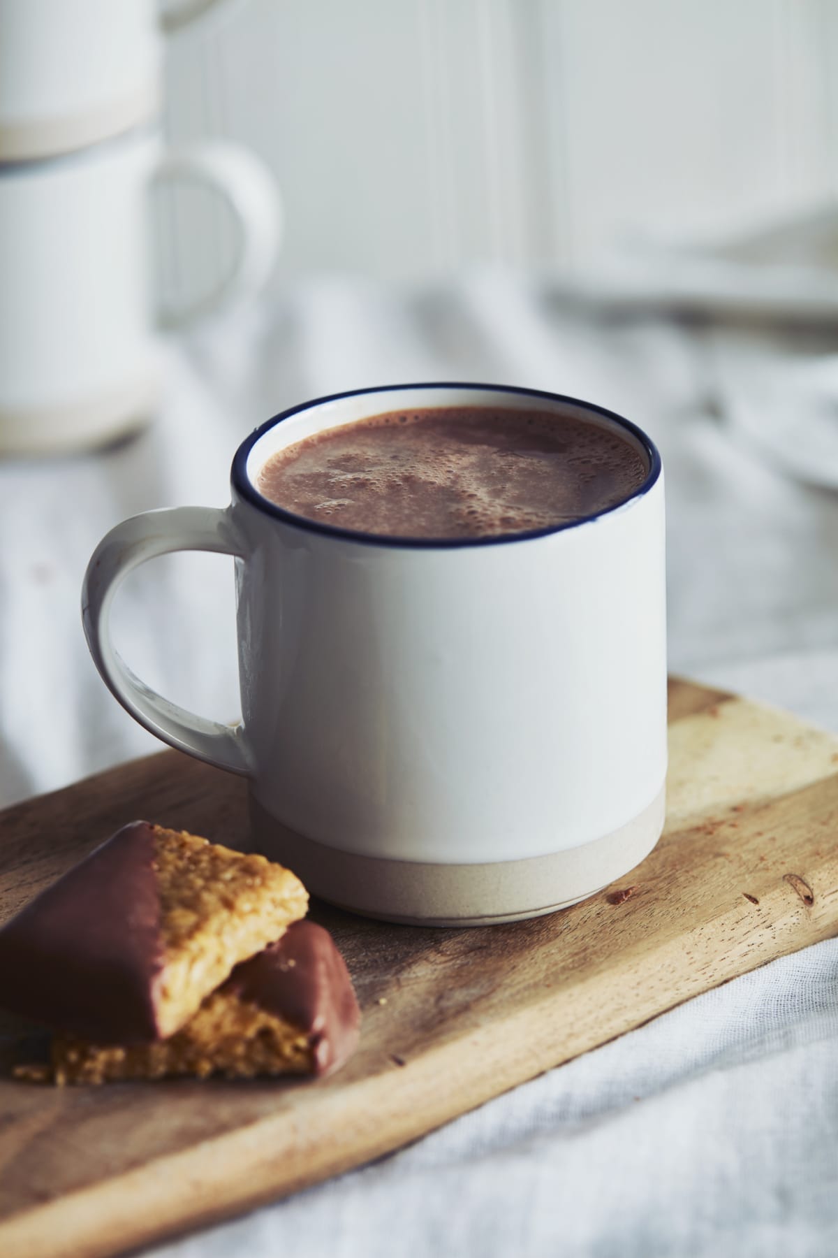 Hot chocolate in mug on wooden board, next to cookie