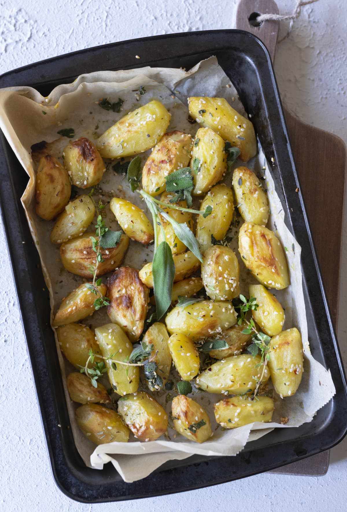 Roasted potatoes in a baking dish with fresh herbs