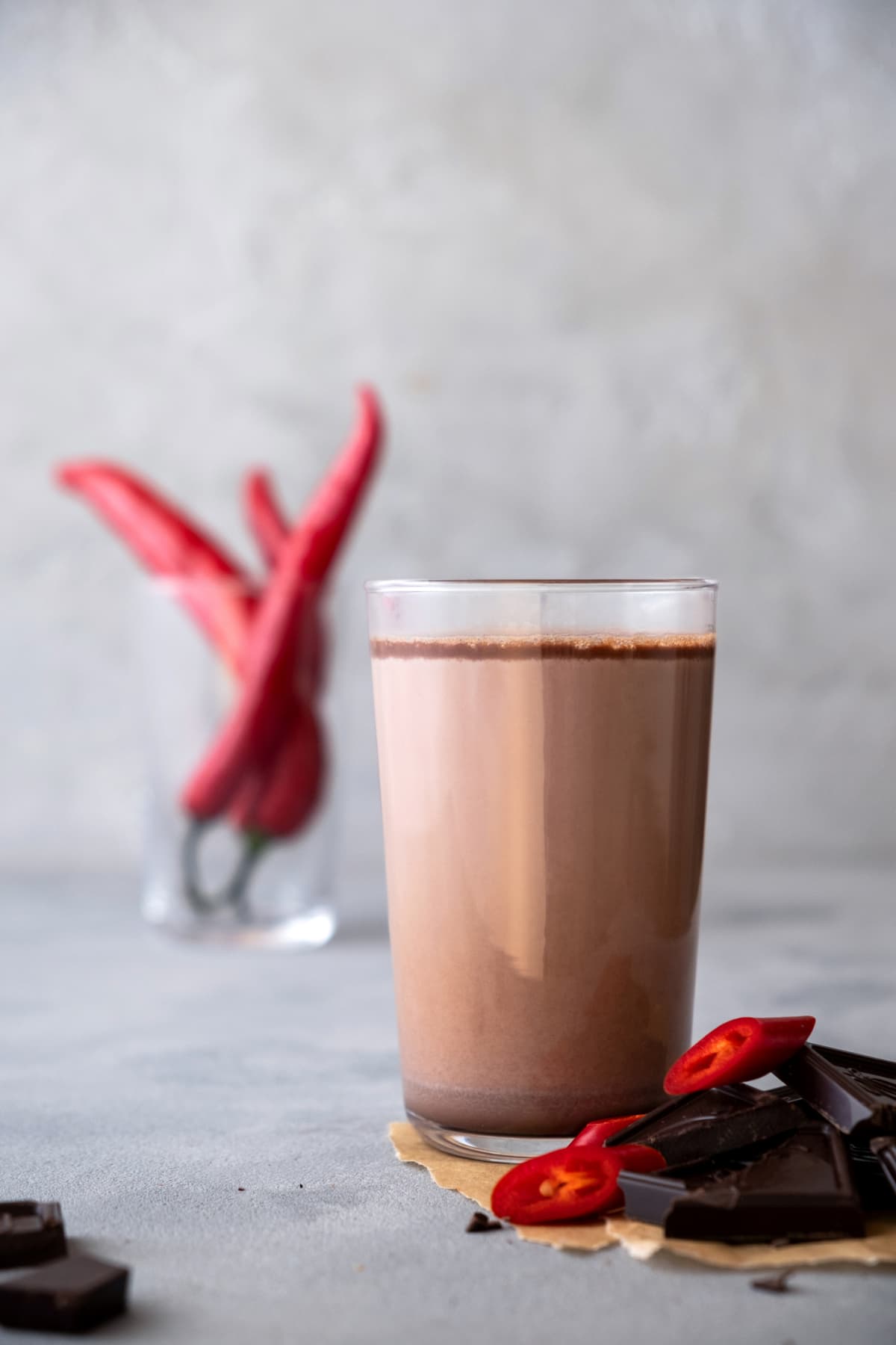 Glass of  hot chocolate, cacao drink with chili pepper. On a gray background