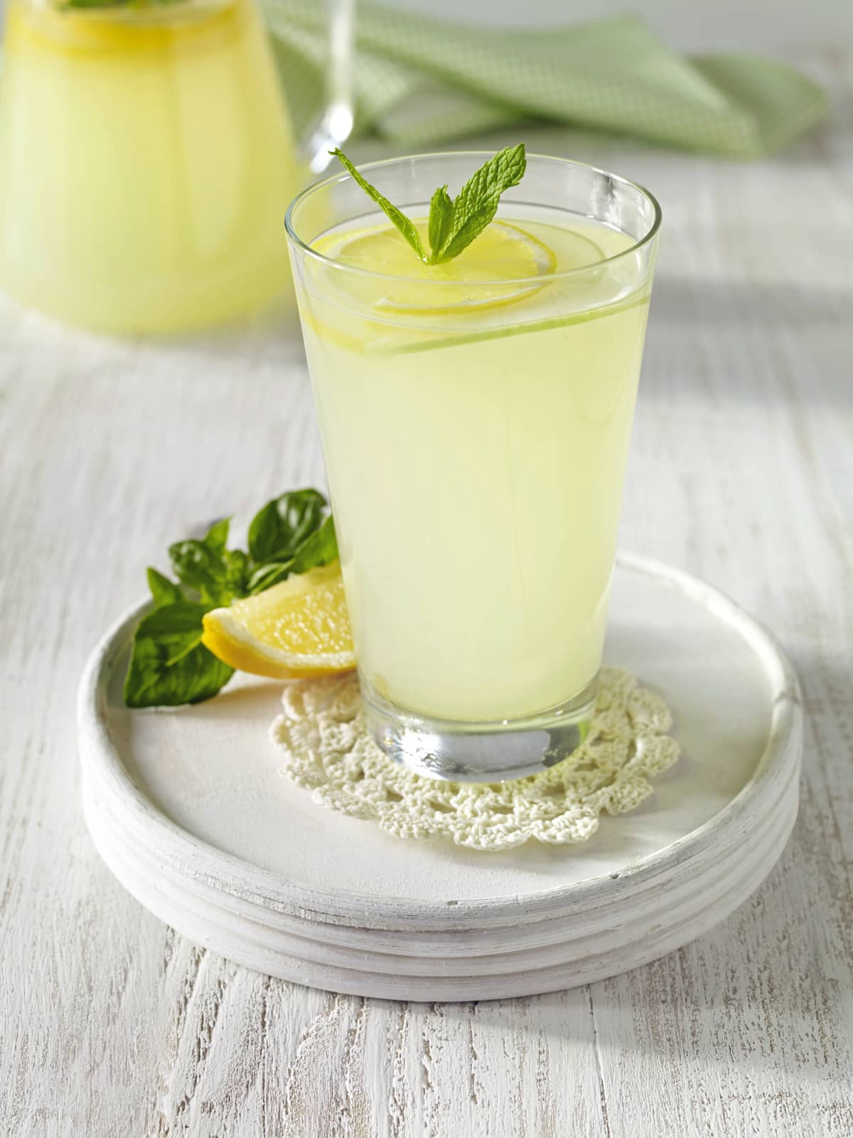 Fresh lemonade with a lemon slice on a white tray on a white wooden table