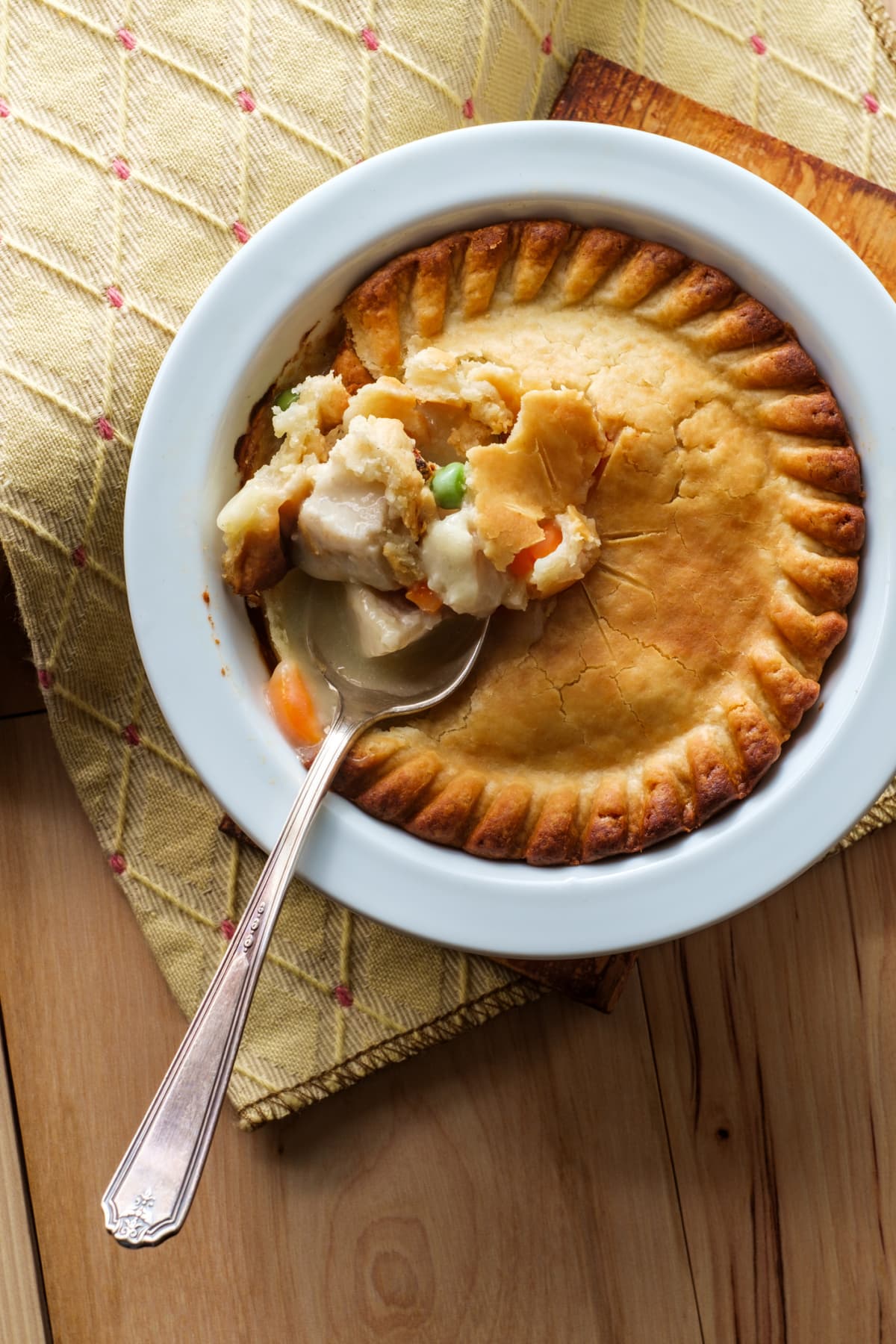 Chicken pot pie with the crust broken by a silver spoon