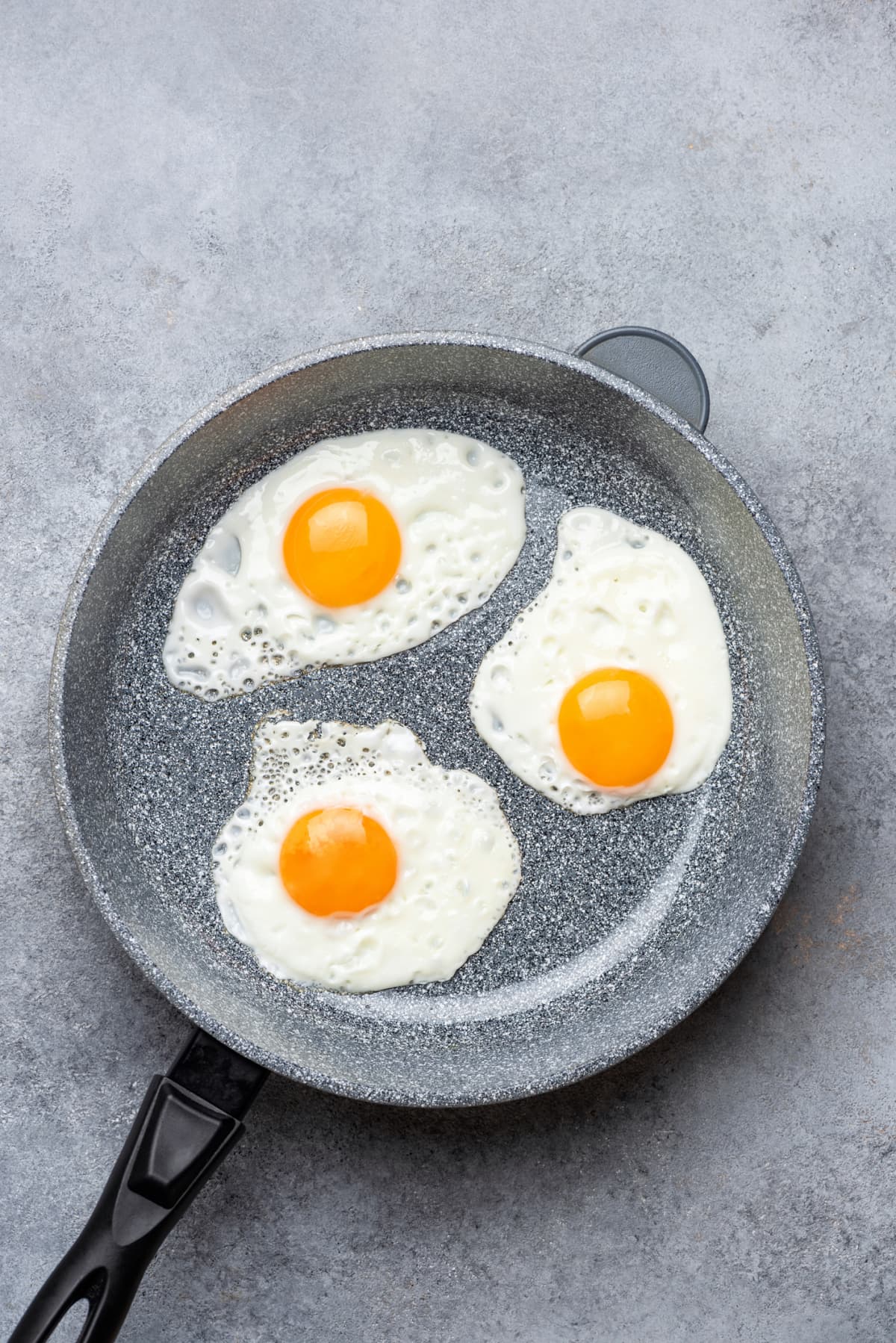Three sunny side up eggs in skillet