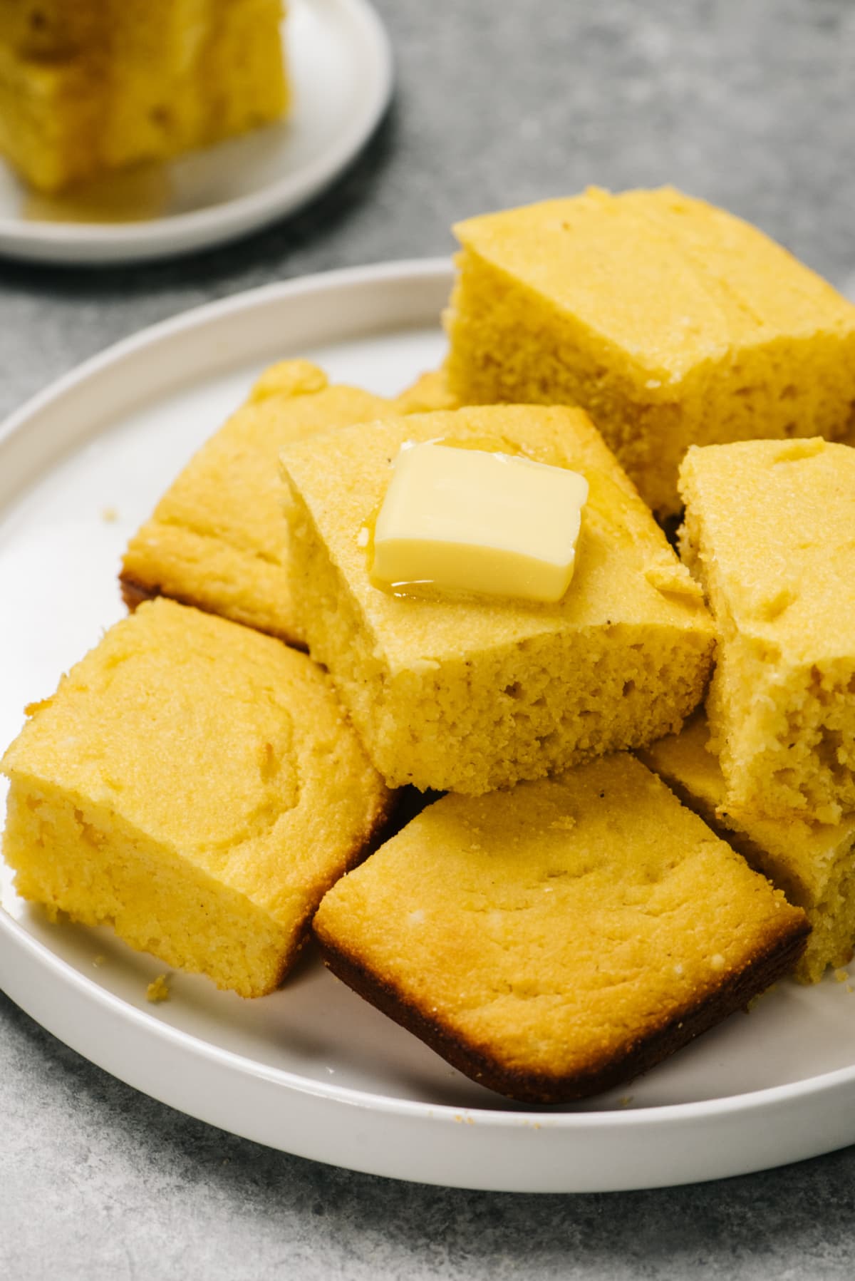 cornbread slices on a plate with a slice of butter on top