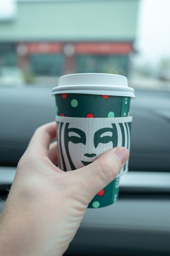 Hand holding a Starbucks green holiday cup.
