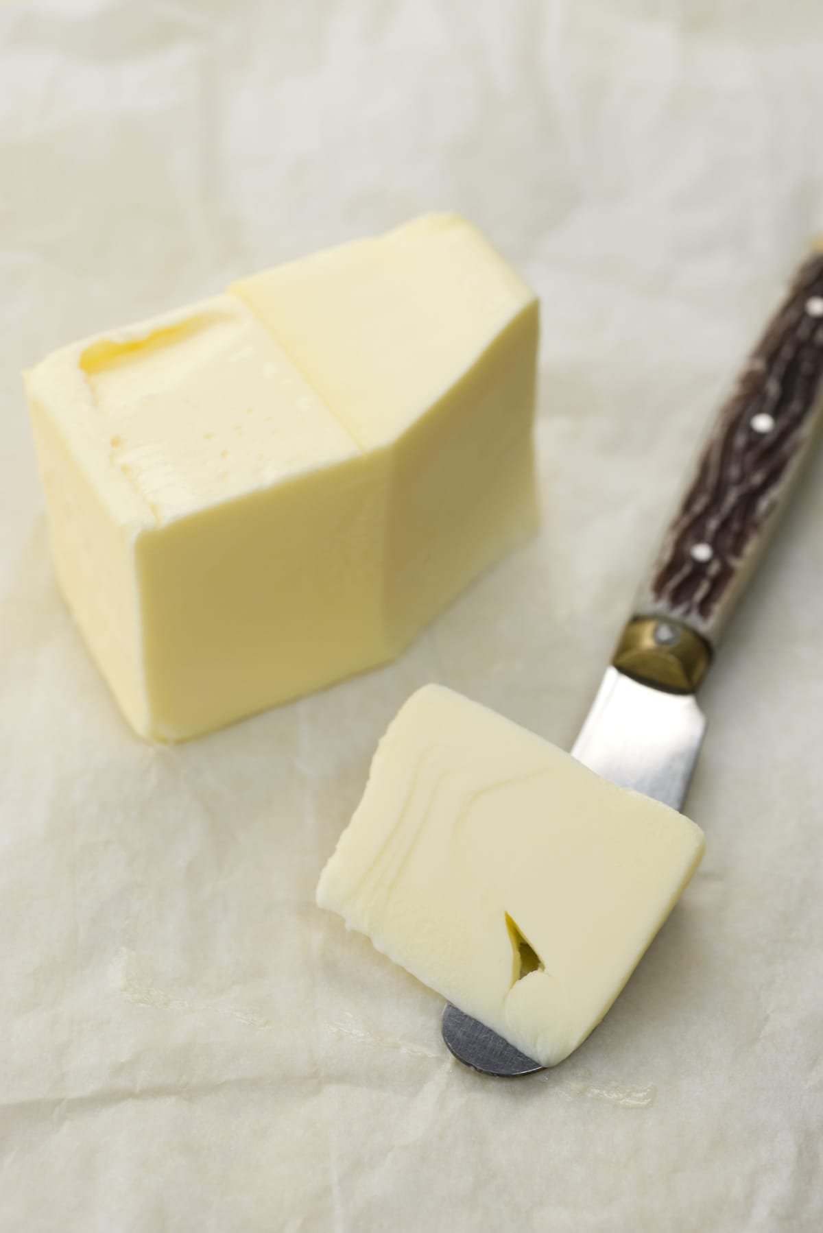 A cut up stick of butter next to a butter knife.