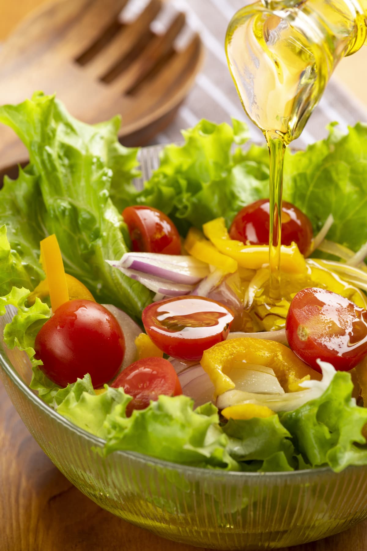 Tomato, onion, and lettuce salad with olive oil in a clear bowl