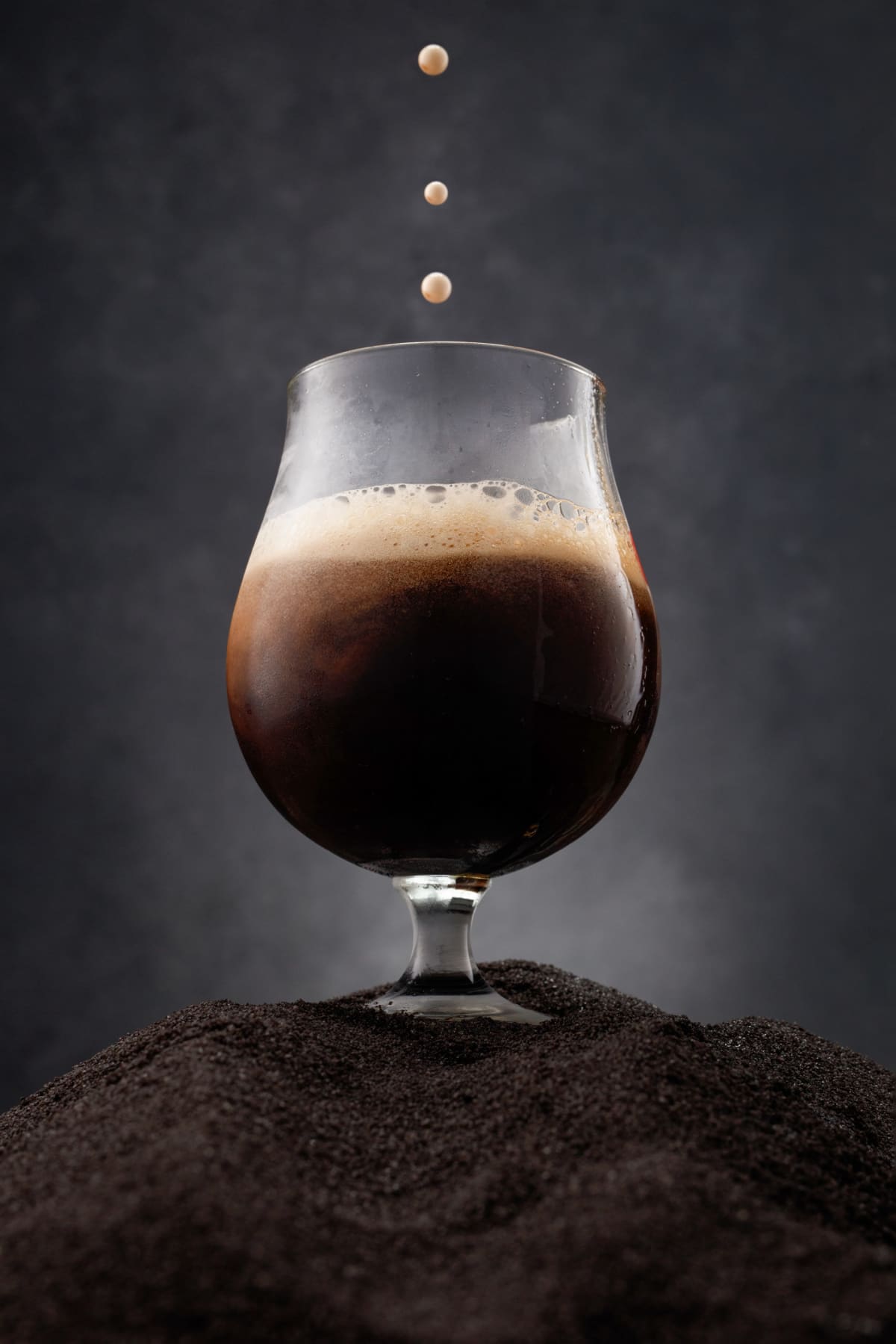 dark stout beer pours into a beer glass with falling drops