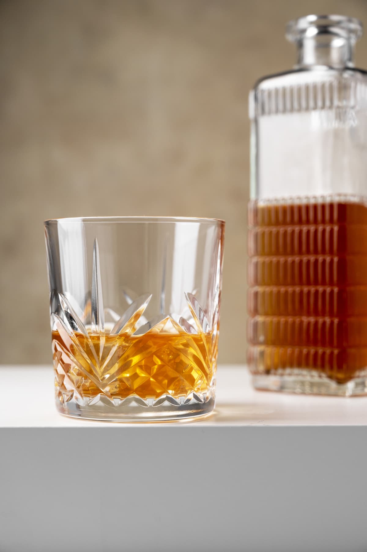 Glass of bourbon next to decanter of bourbon