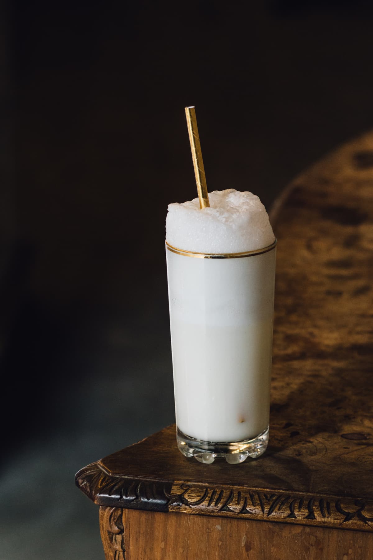 White Ramos Gin Fizz cocktail. milkshake with gold straw and gold rim