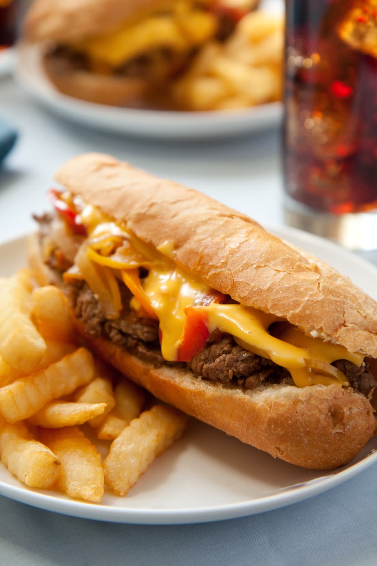 Philly cheesesteak on plate with fries