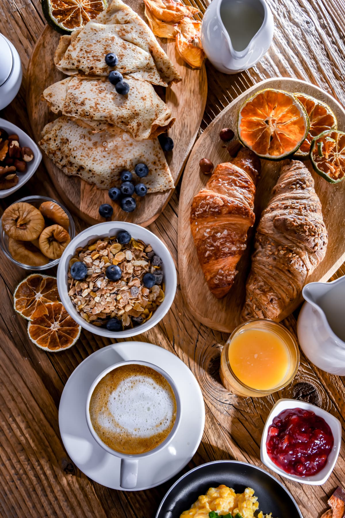Spread of breakfast foods including oats, croissants, berries, and crepes