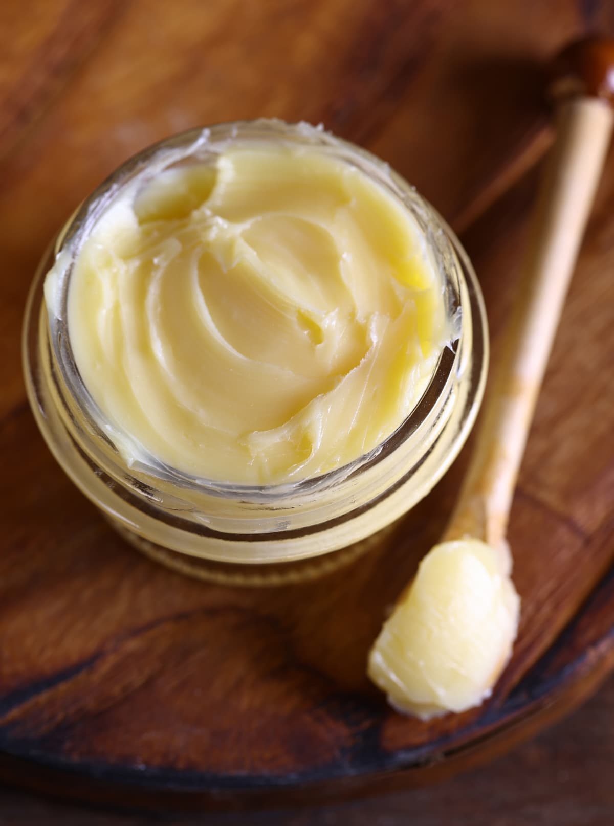 Glass jar of butter with wooden spoon on the side