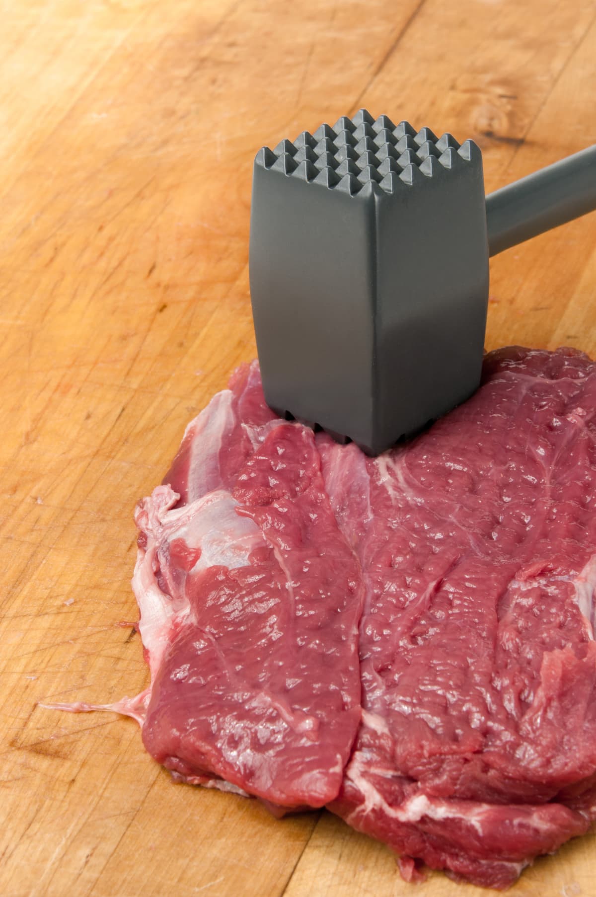 Meat being tenderized with metal meat mallet