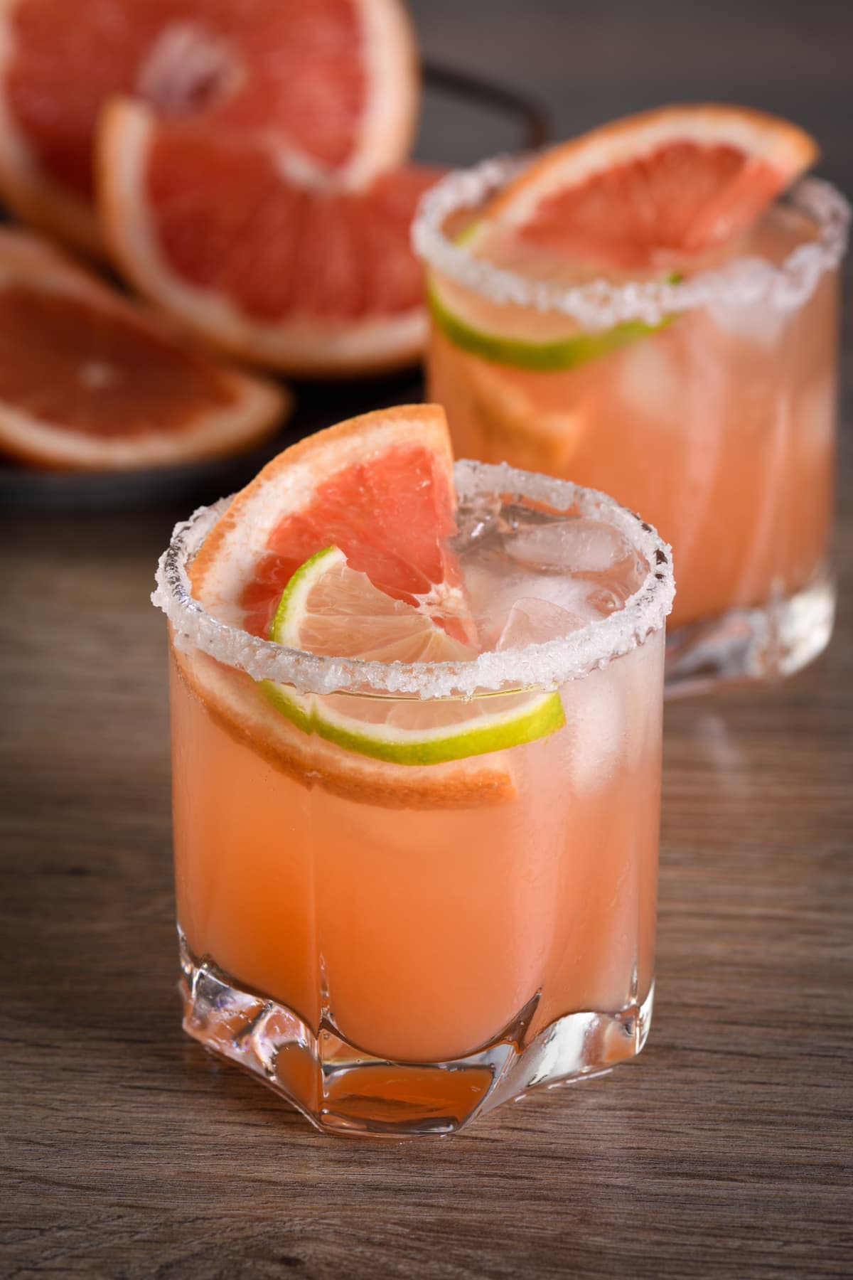 Pink Paloma cocktail in a salted glass with a grapefruit