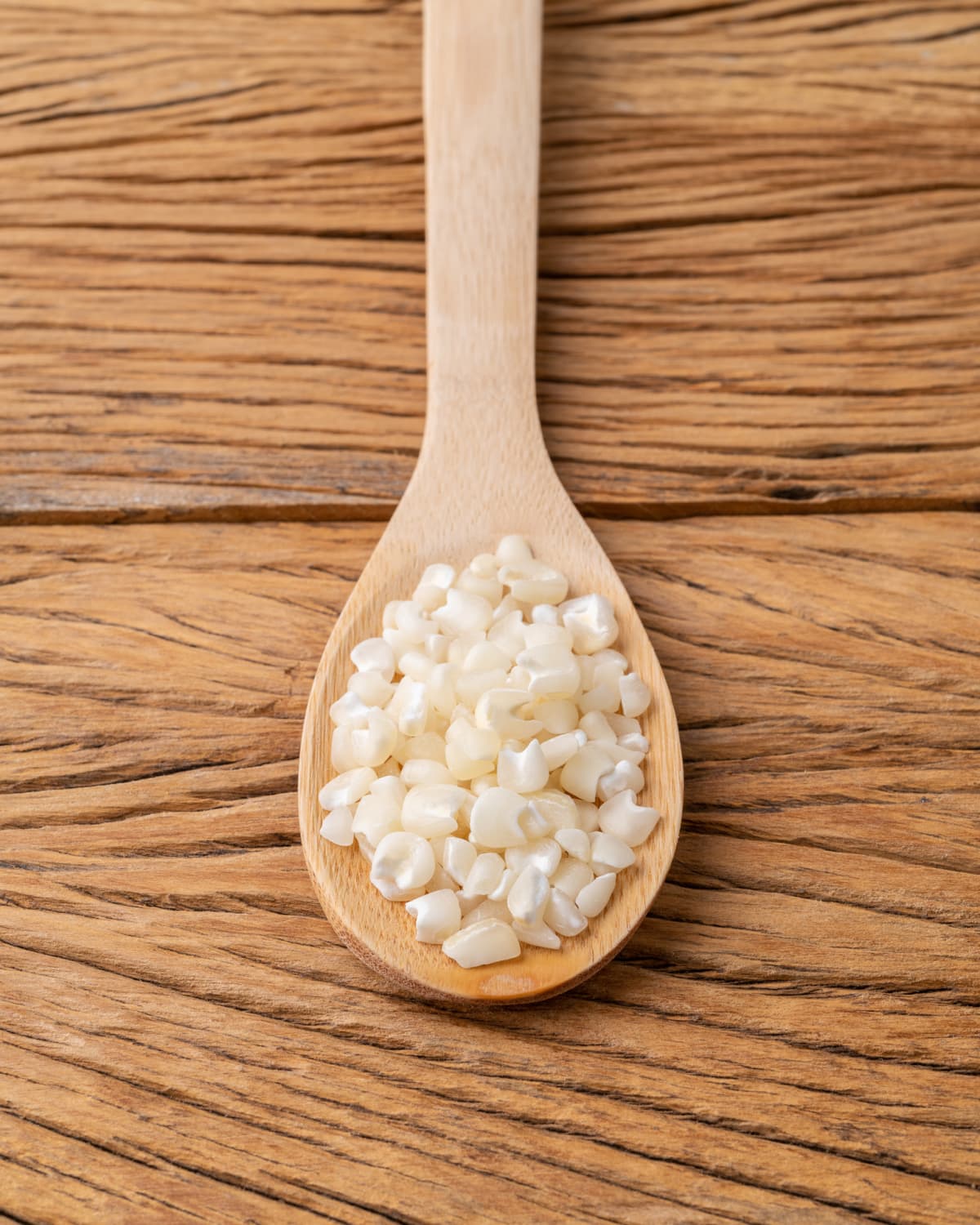 Dried hominy in a wooden spoon over a table
