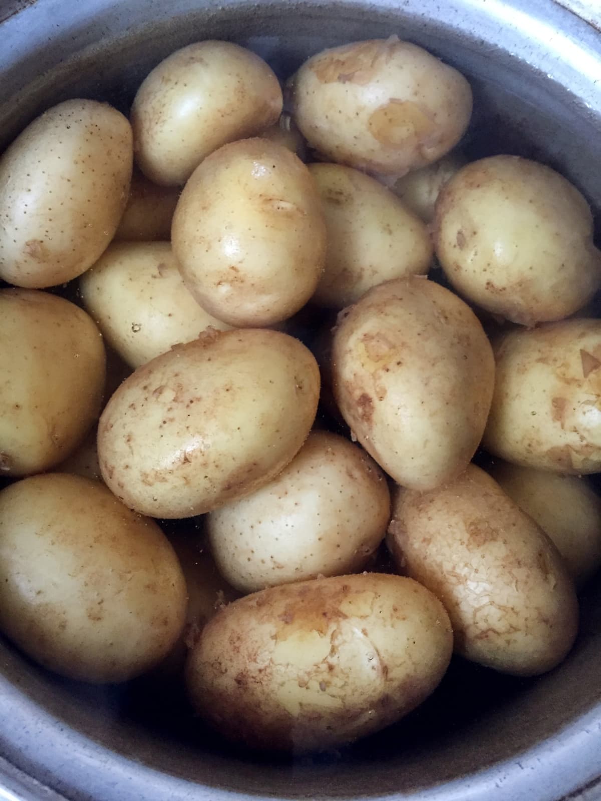 Whole potatoes boiling in water in a cooking pan