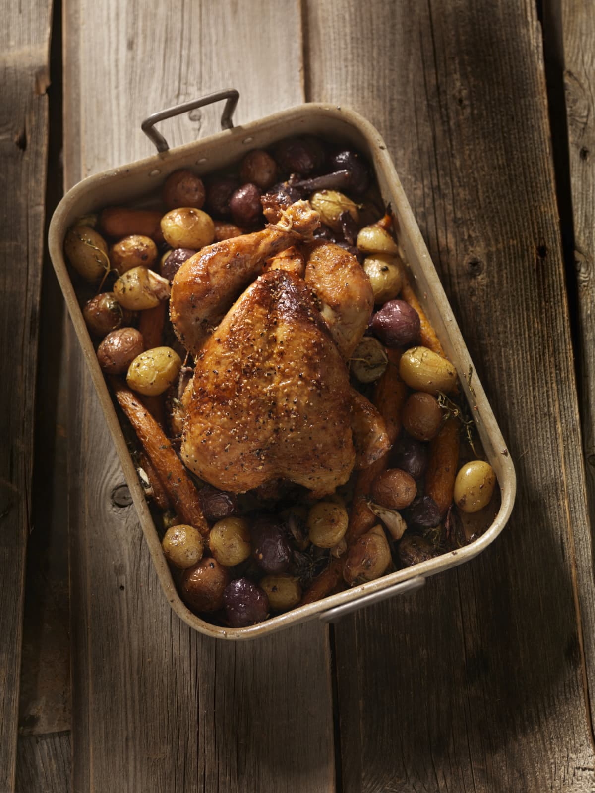 Roasted chicken with carrots and potatoes on a baking pan