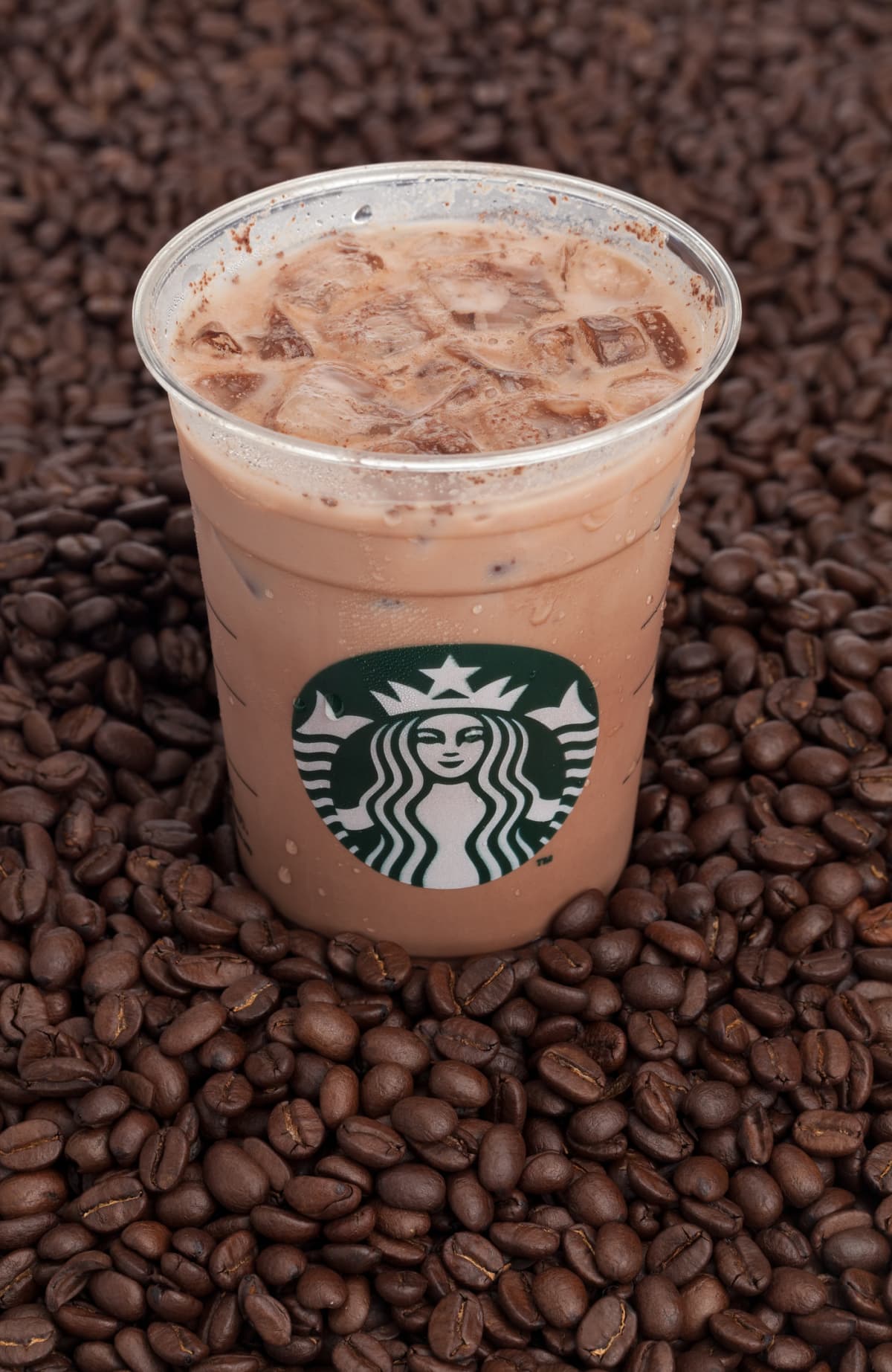 Starbucks iced coffee with a bunch of coffee beans around it