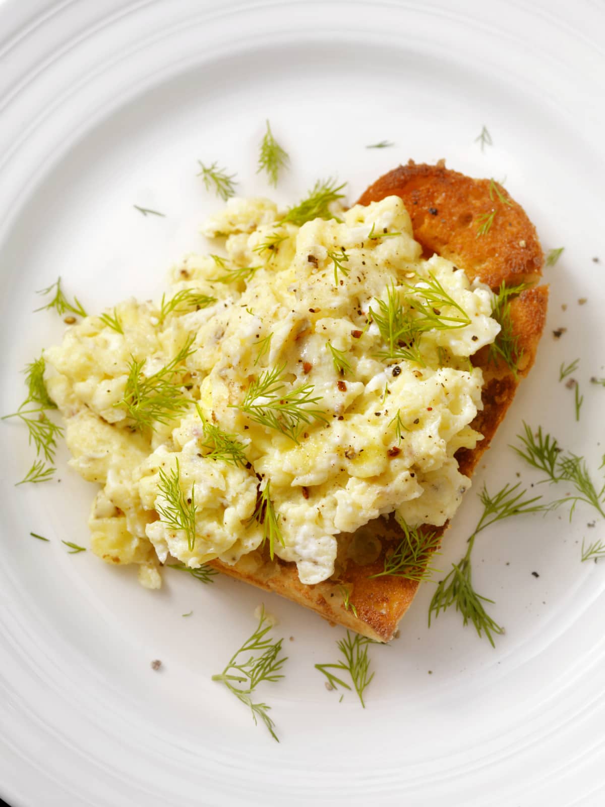 Closeup of scrambled eggs and toast on white plate