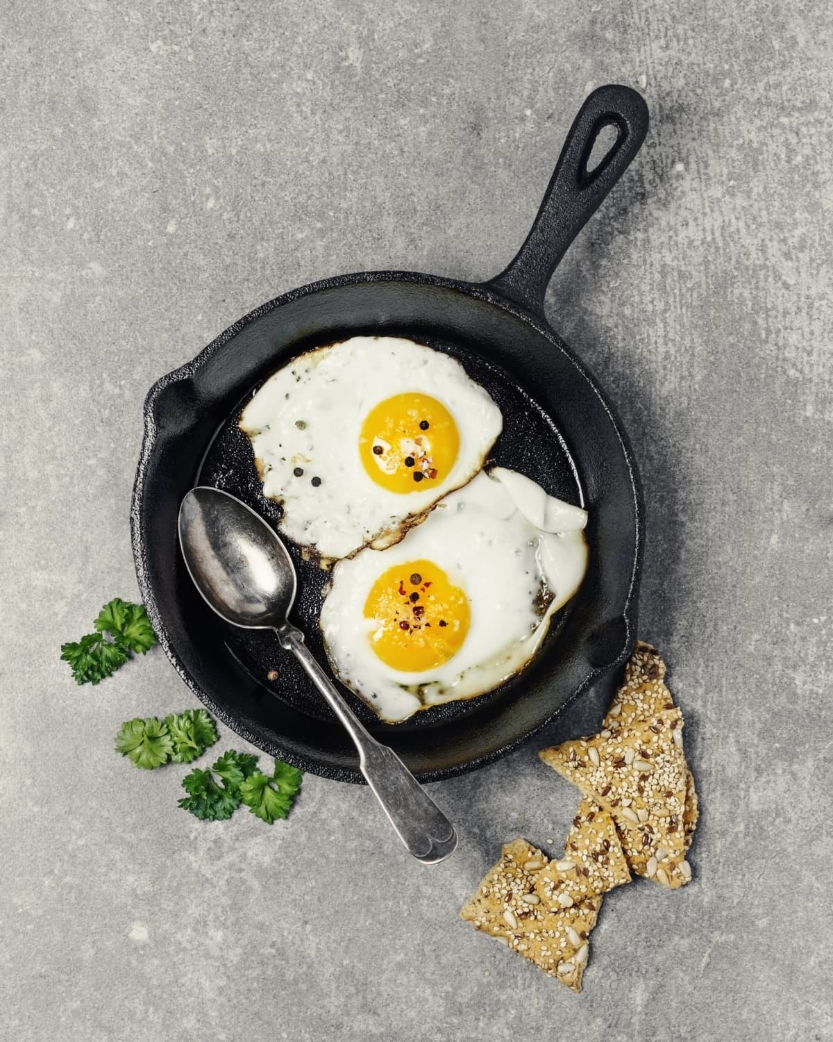 Fried eggs in a skillet against a wooden backdrop.