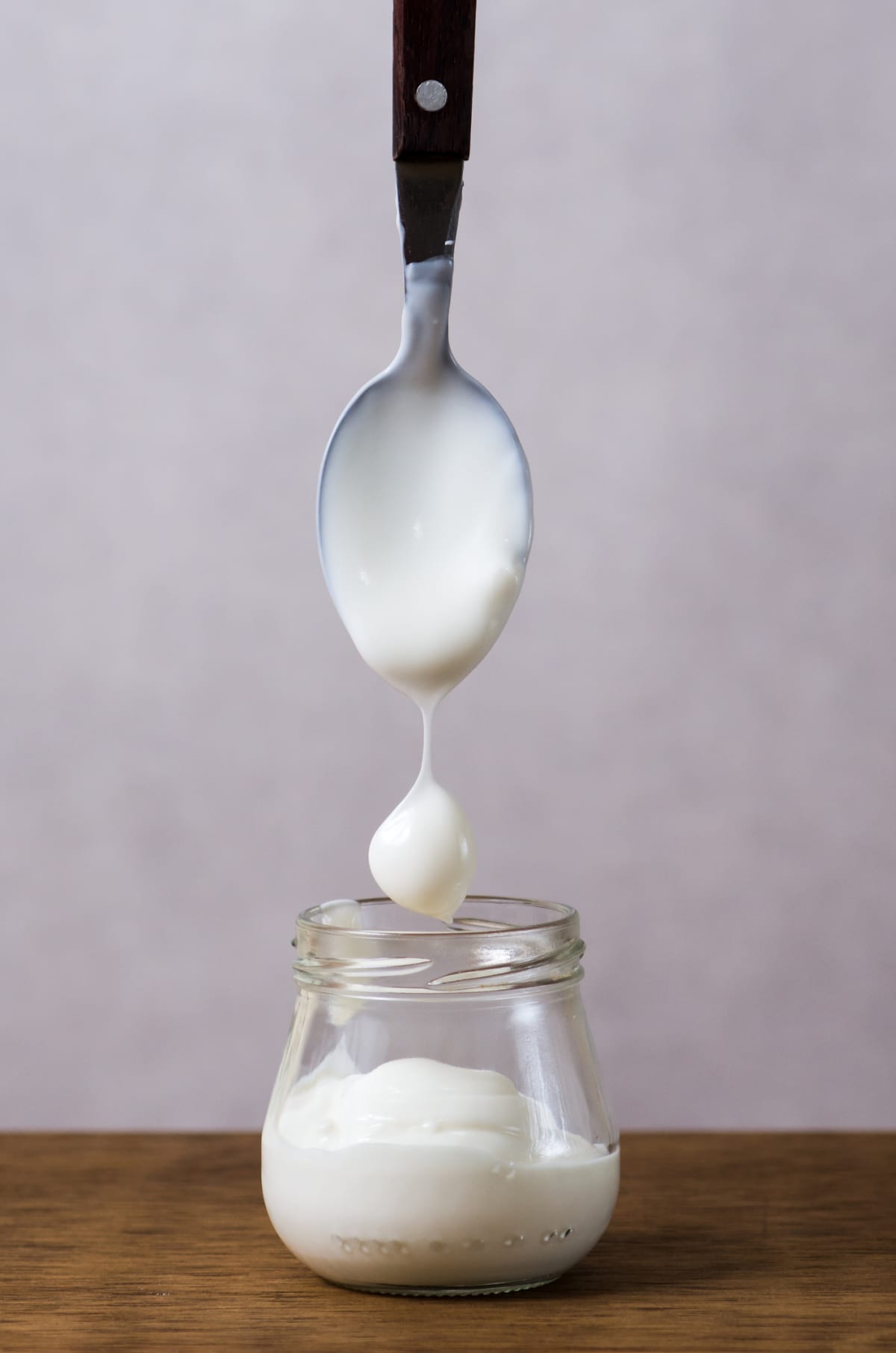 Spoon dropping dollop of yogurt into jar