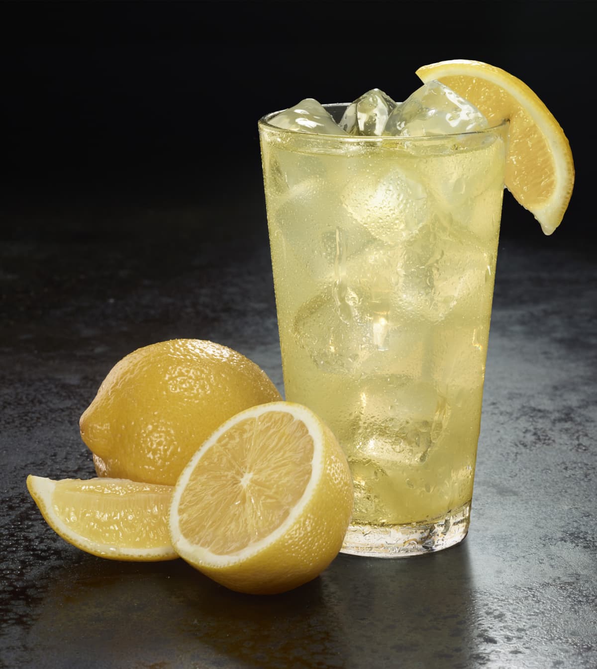 Iced lemonade with lemons against a dark background.