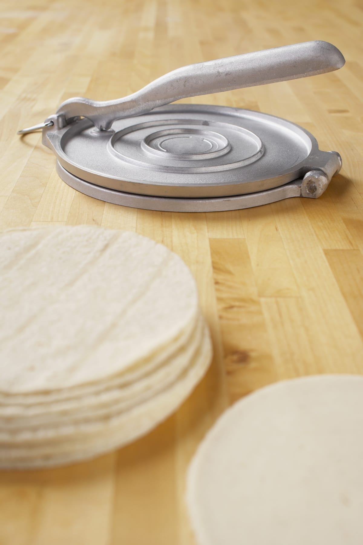 Tortilla press next to stack of flour tortillas