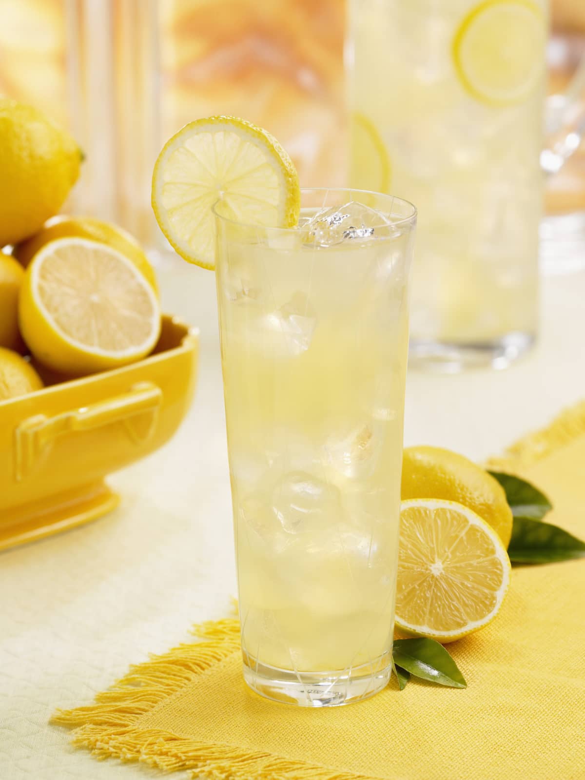 Fresh lemonade on a white table top with green garnish and a lemon slice