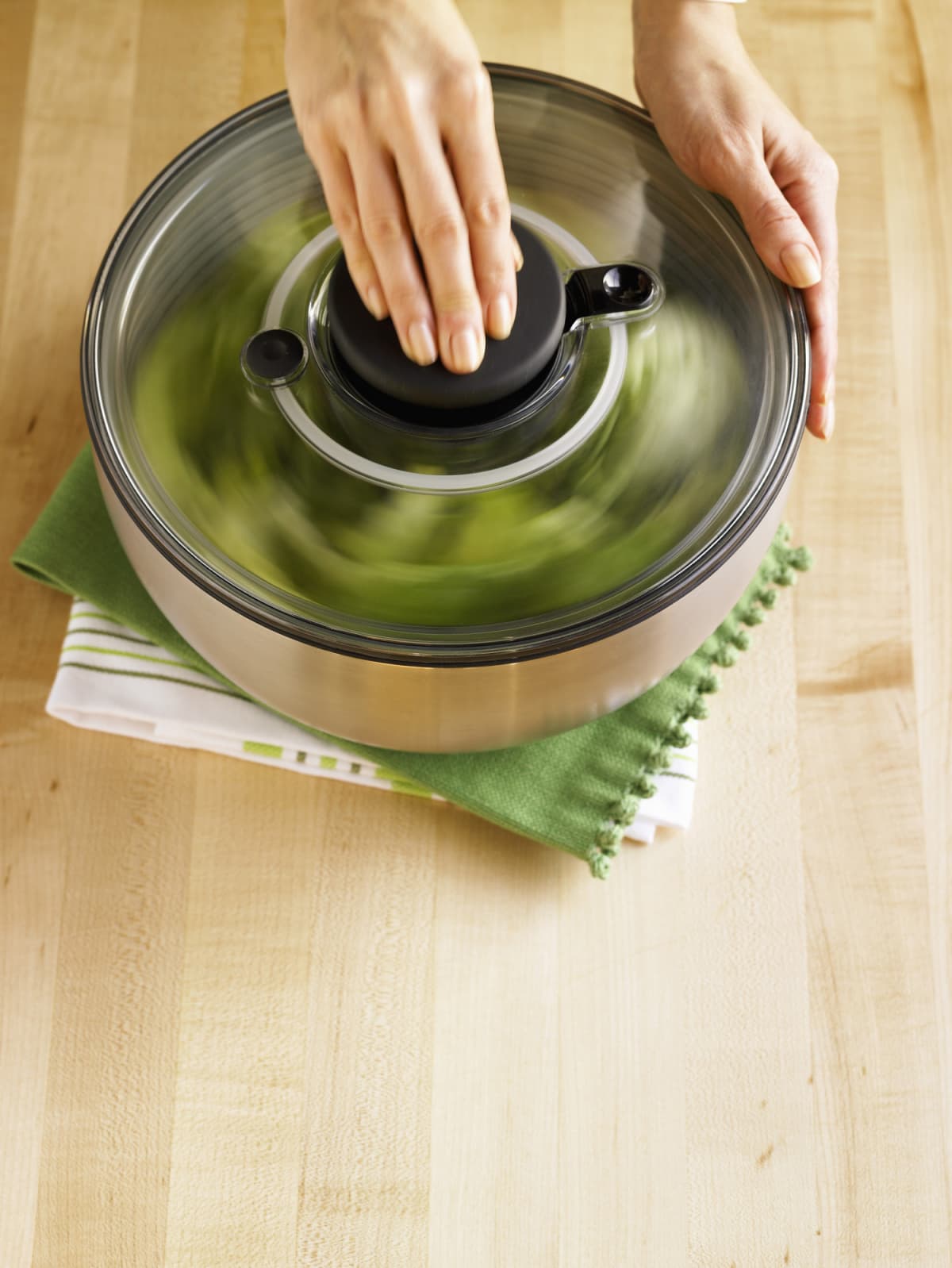 Hands using a salad spinner