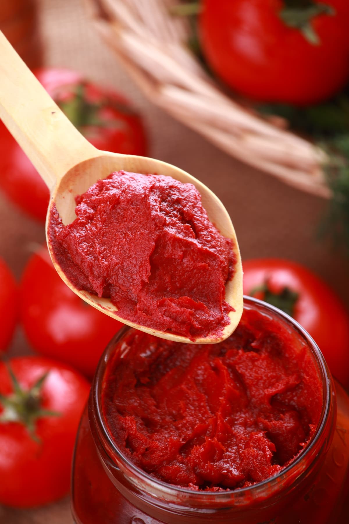 Tomato paste on a spoon while some is in a jar