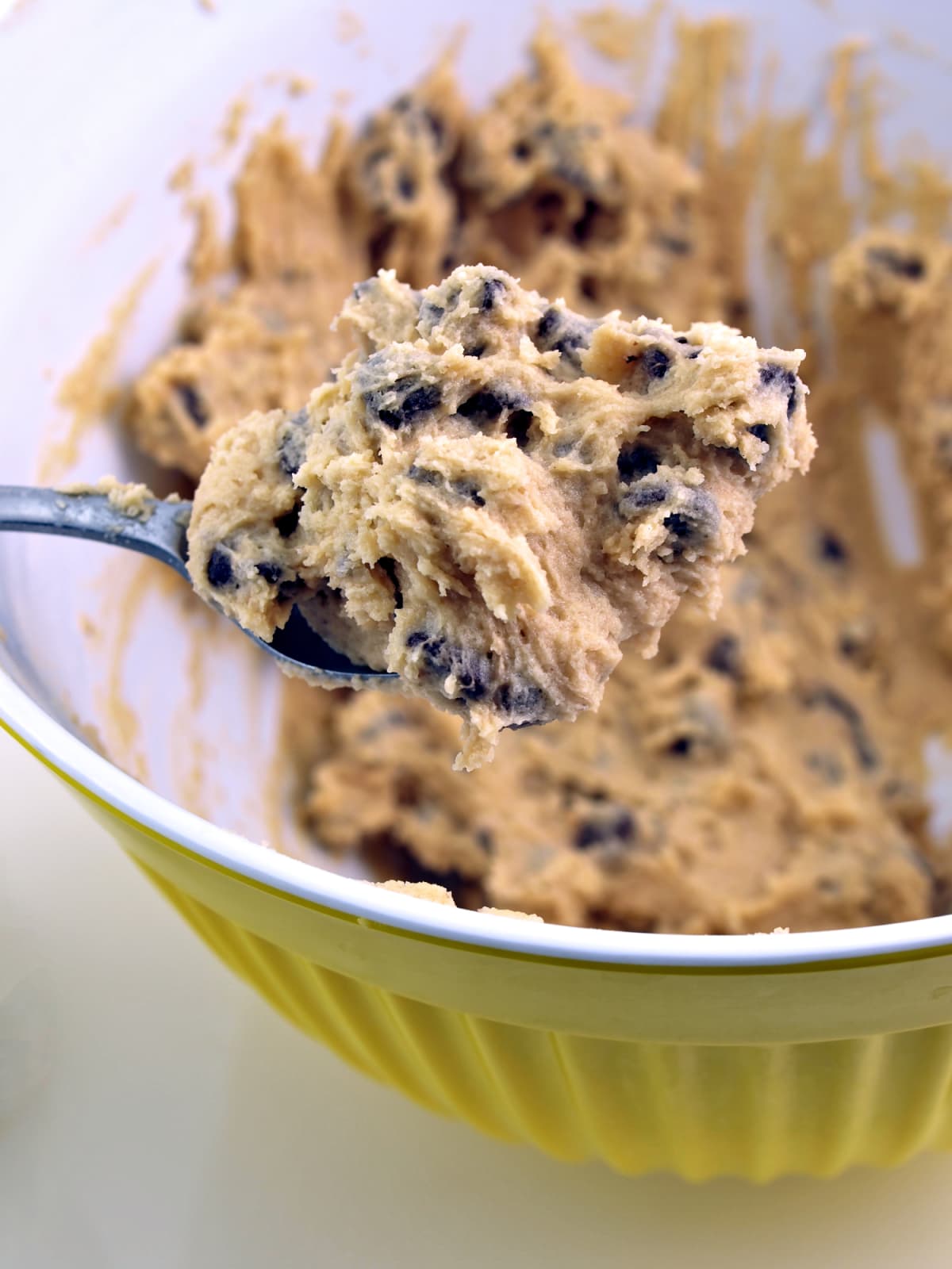 Spoon full of cookie dough above bowl of cookie dough