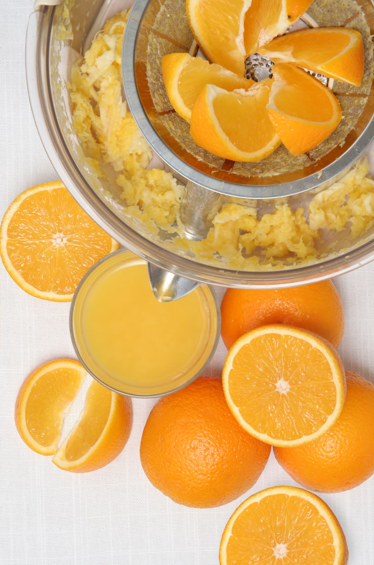 Freshly squeezed orange juice, a juicer juicing oranges, and oranges