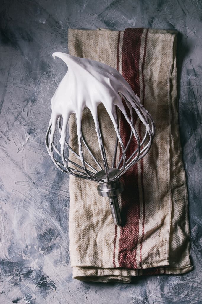 A whisk covered in meringue