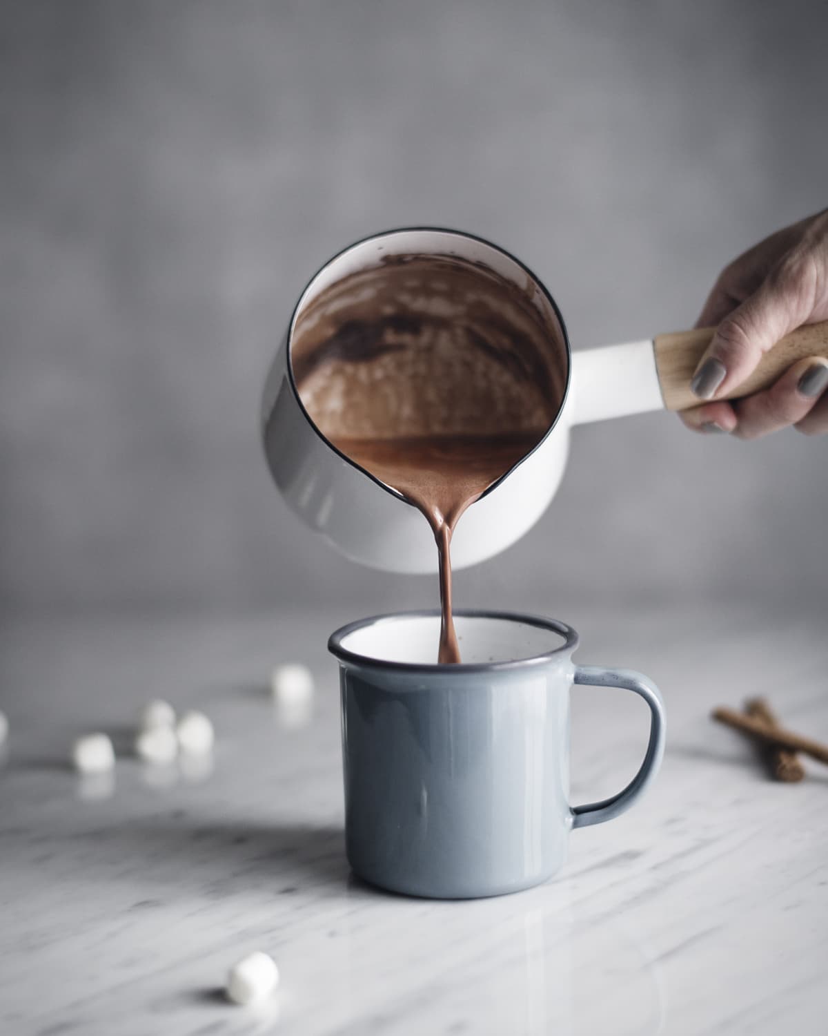 Pouring hot chocolate from pot to mug
