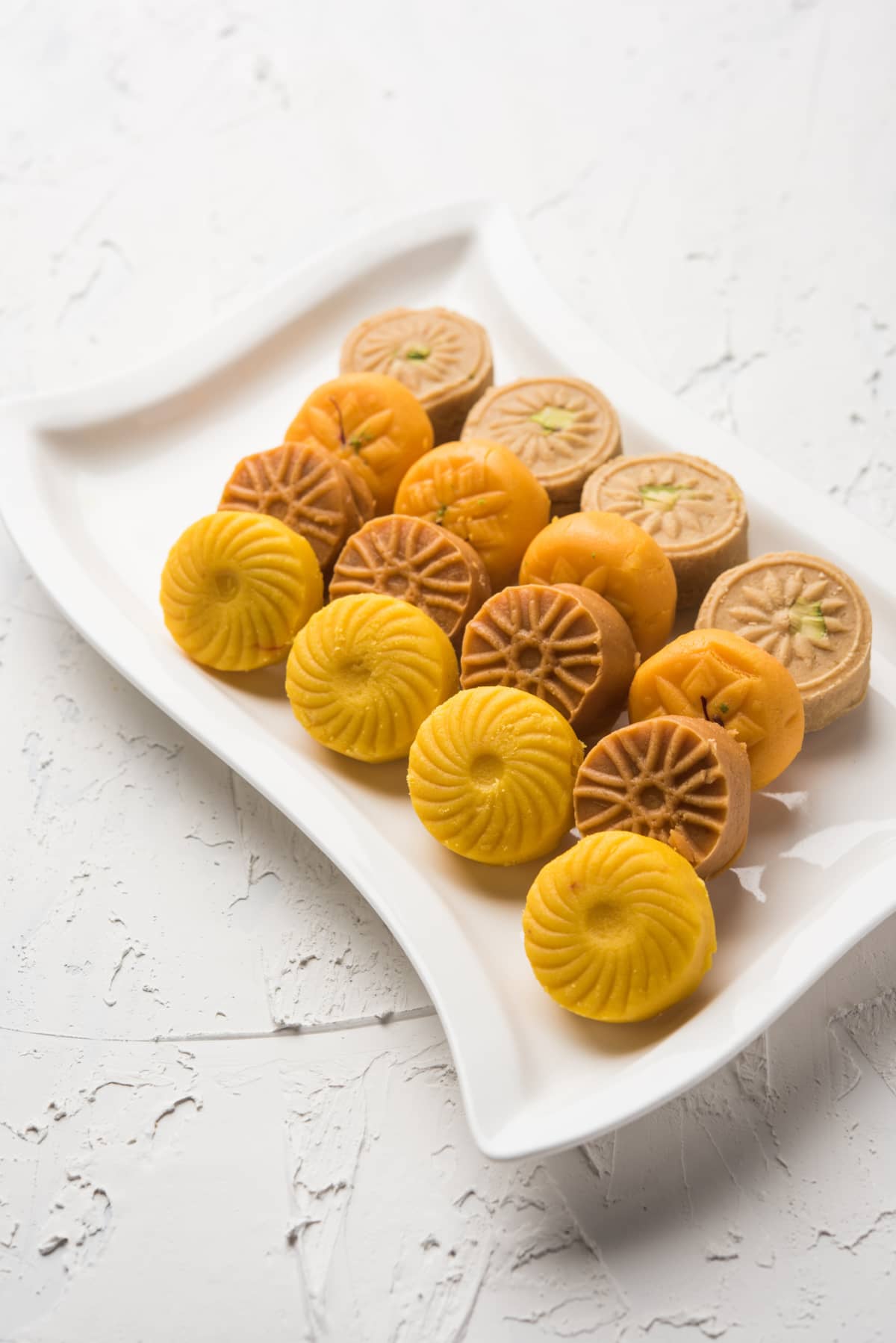 Variety of Peda / Pedha Served in a bowl or plate over white background or with pile of gifts. It's a popular festival food from India. selective focus