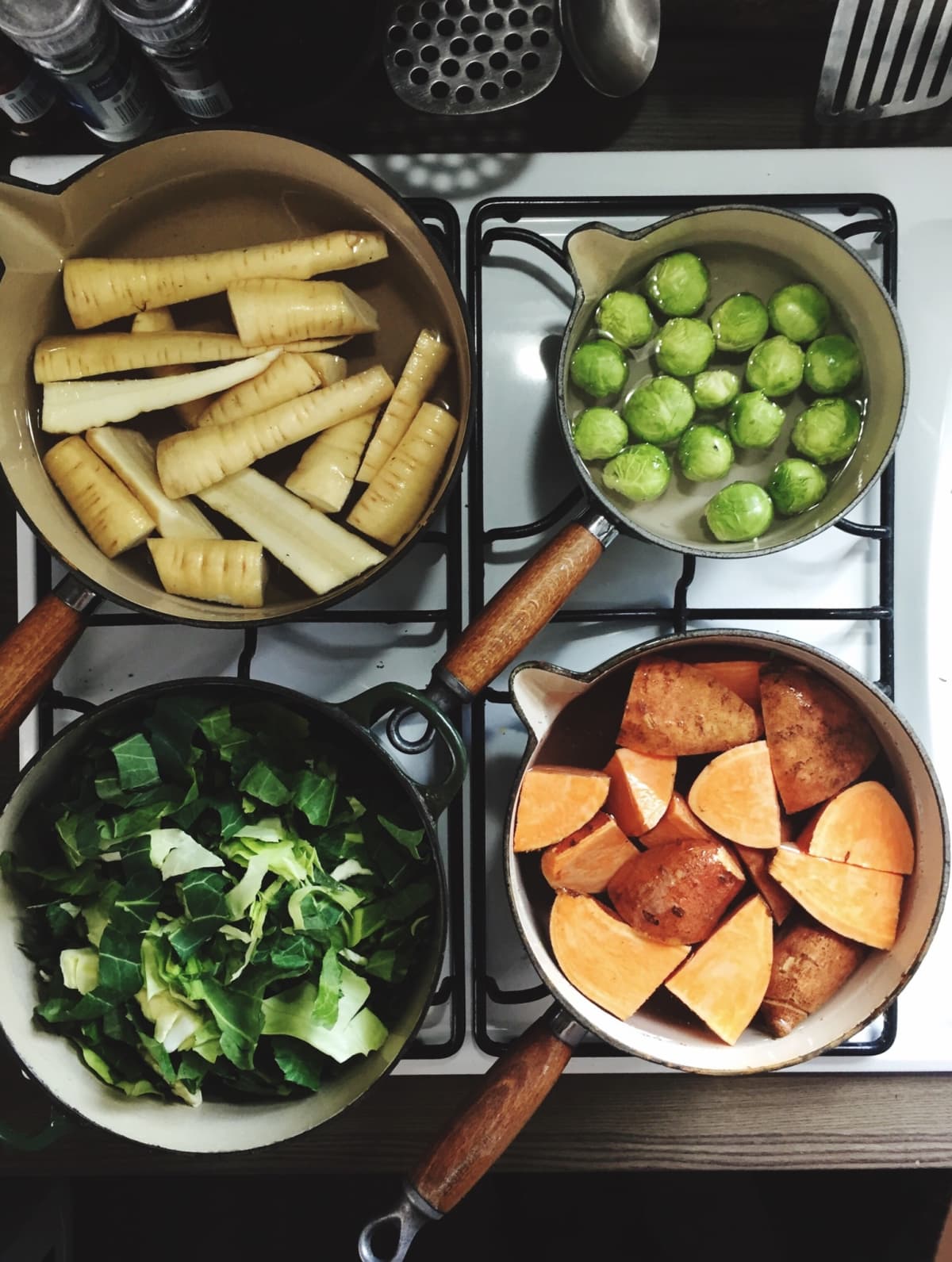 Stovetop area with vegetables like Brussels sprouts cooking in pots