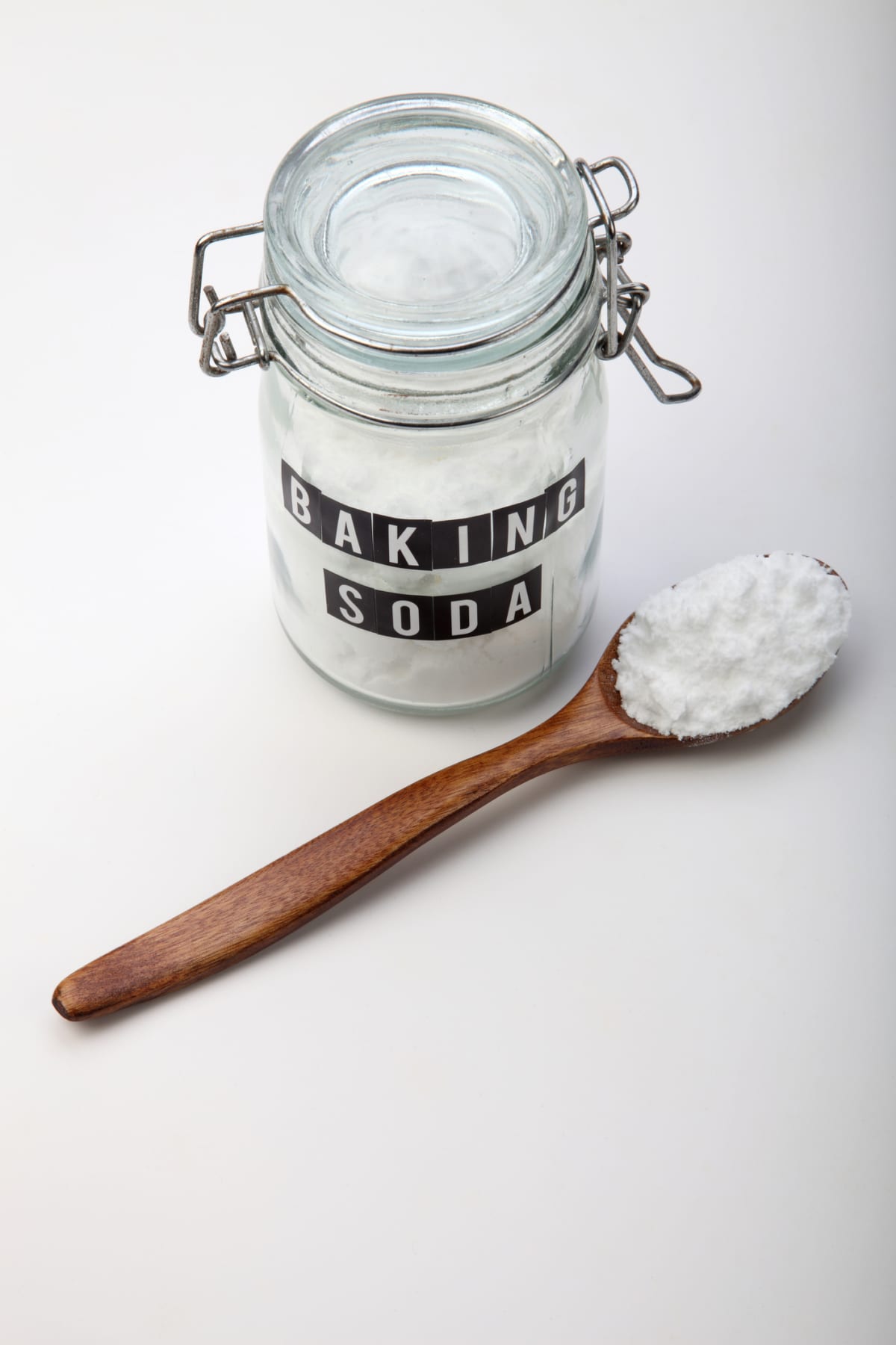 A jar of baking soda next to a spoon