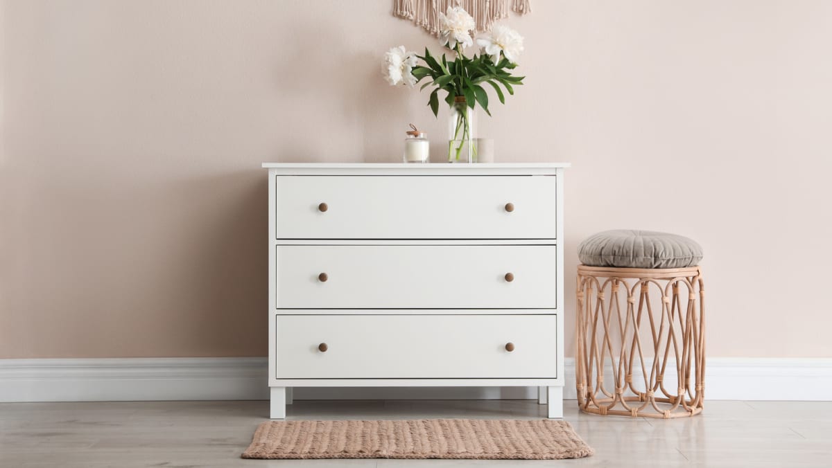 a white dresser with a flower on top