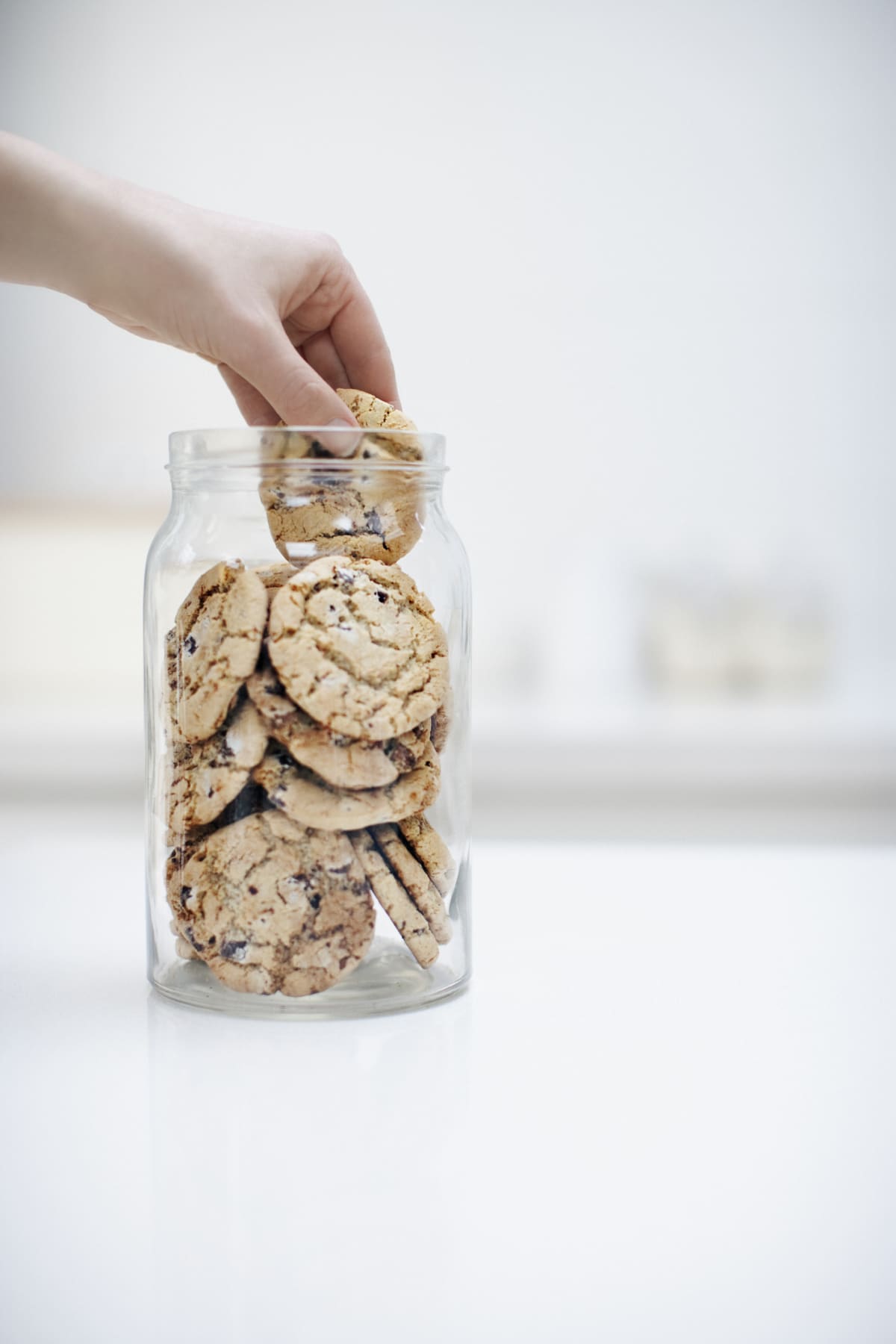 a hand taking a cookie out of a cookie jar