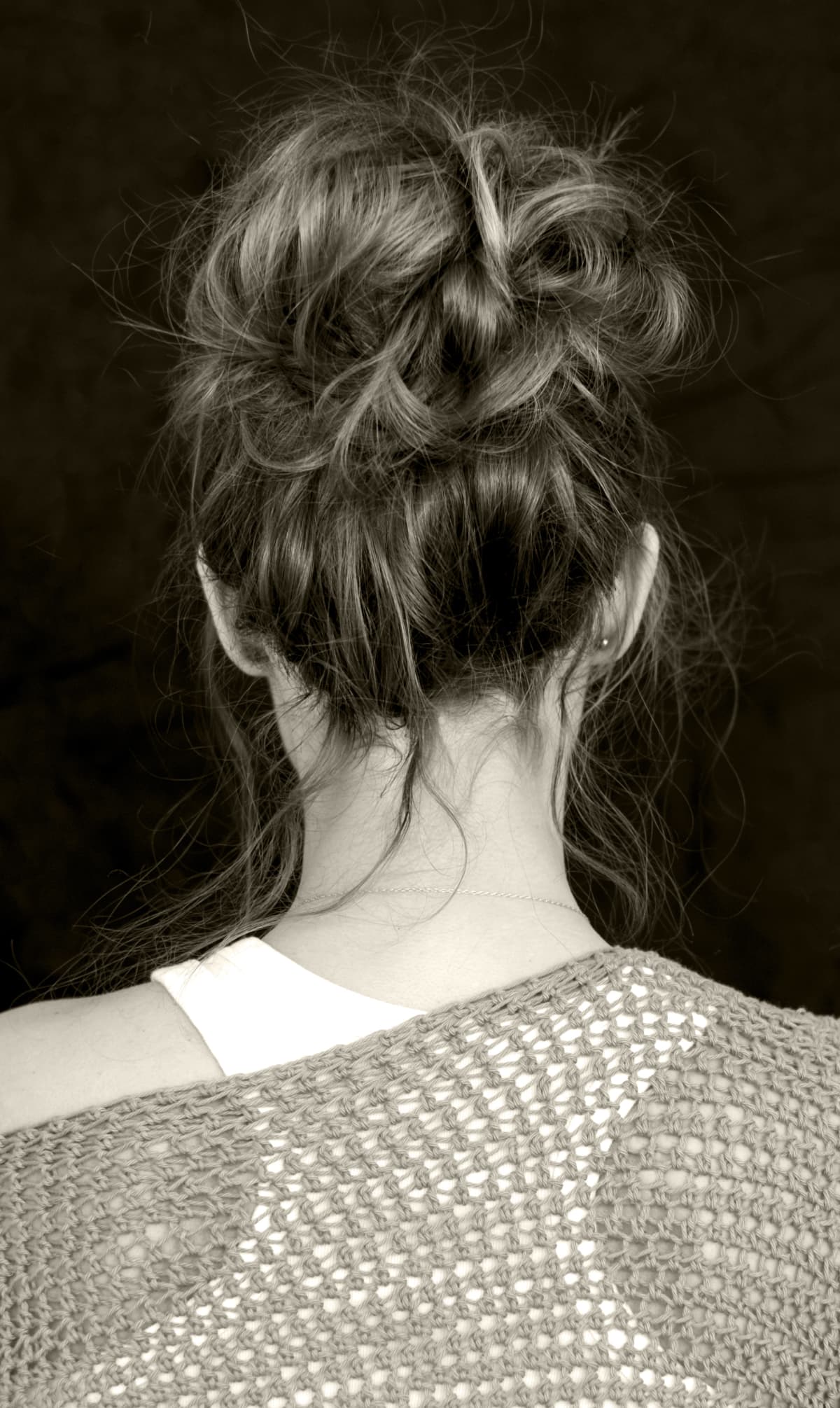 a woman with her back turned wearing a messy bun