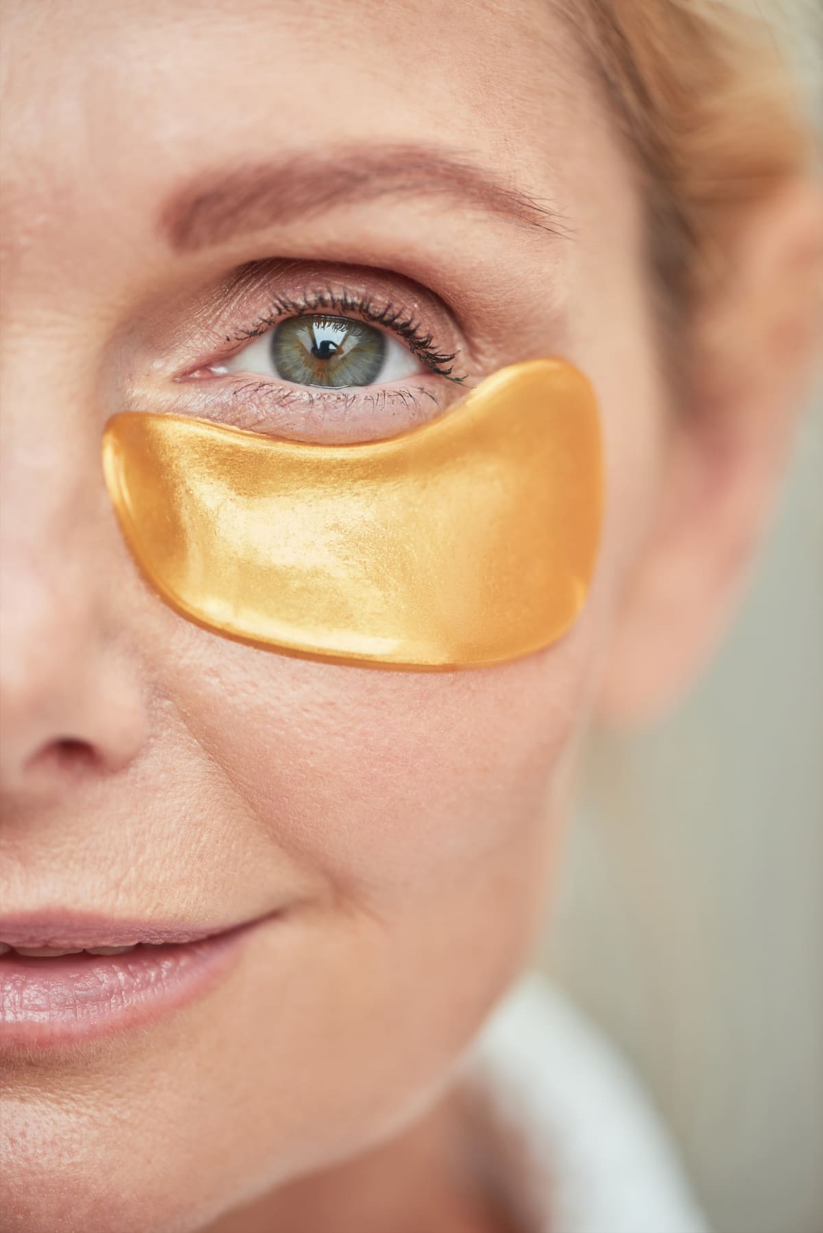 Under eye lotion. Skin moisturizing. Anti-aging cosmetology. Beautiful woman applying cream product on fresh radiant face on white background.