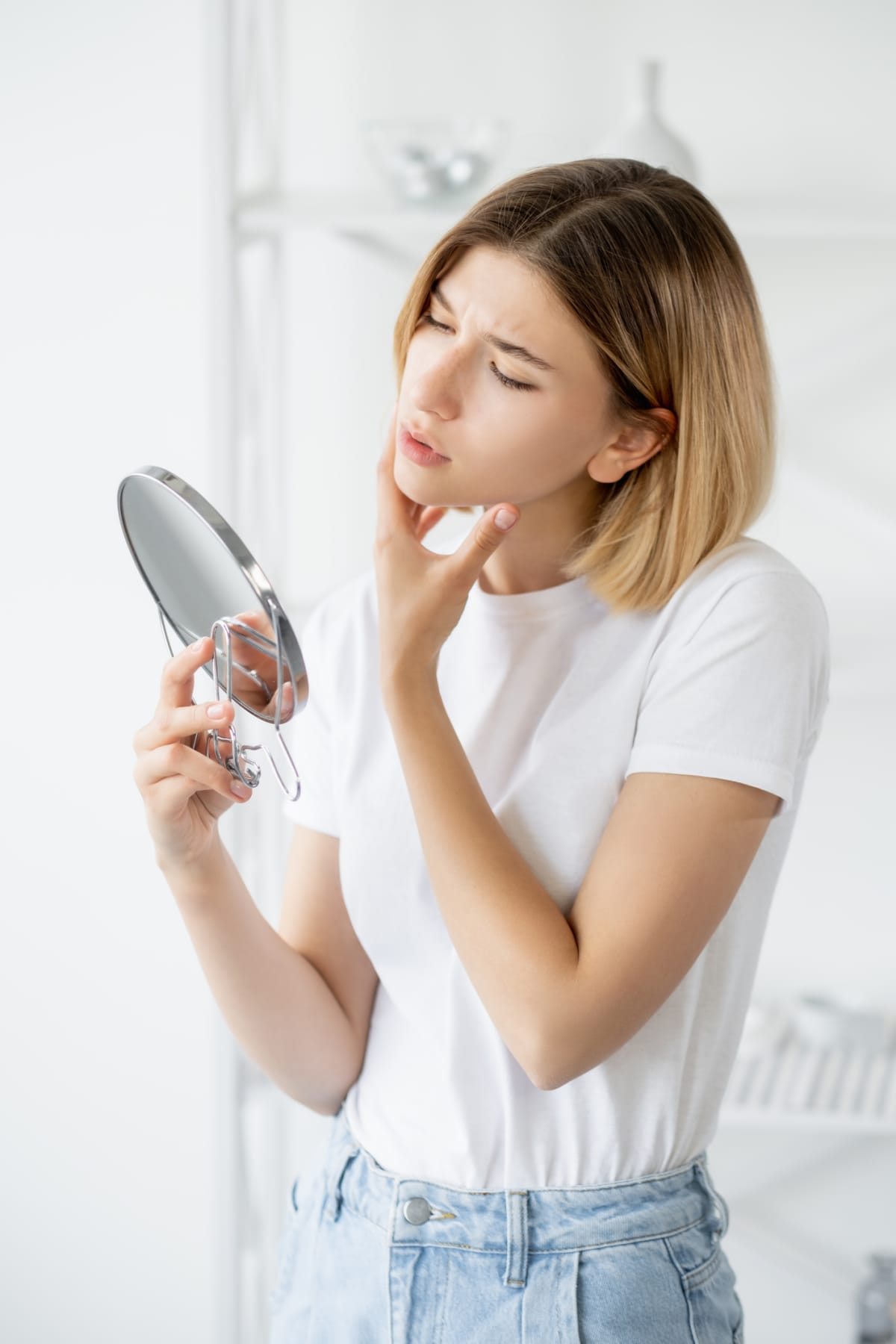woman examining her face in the mirror