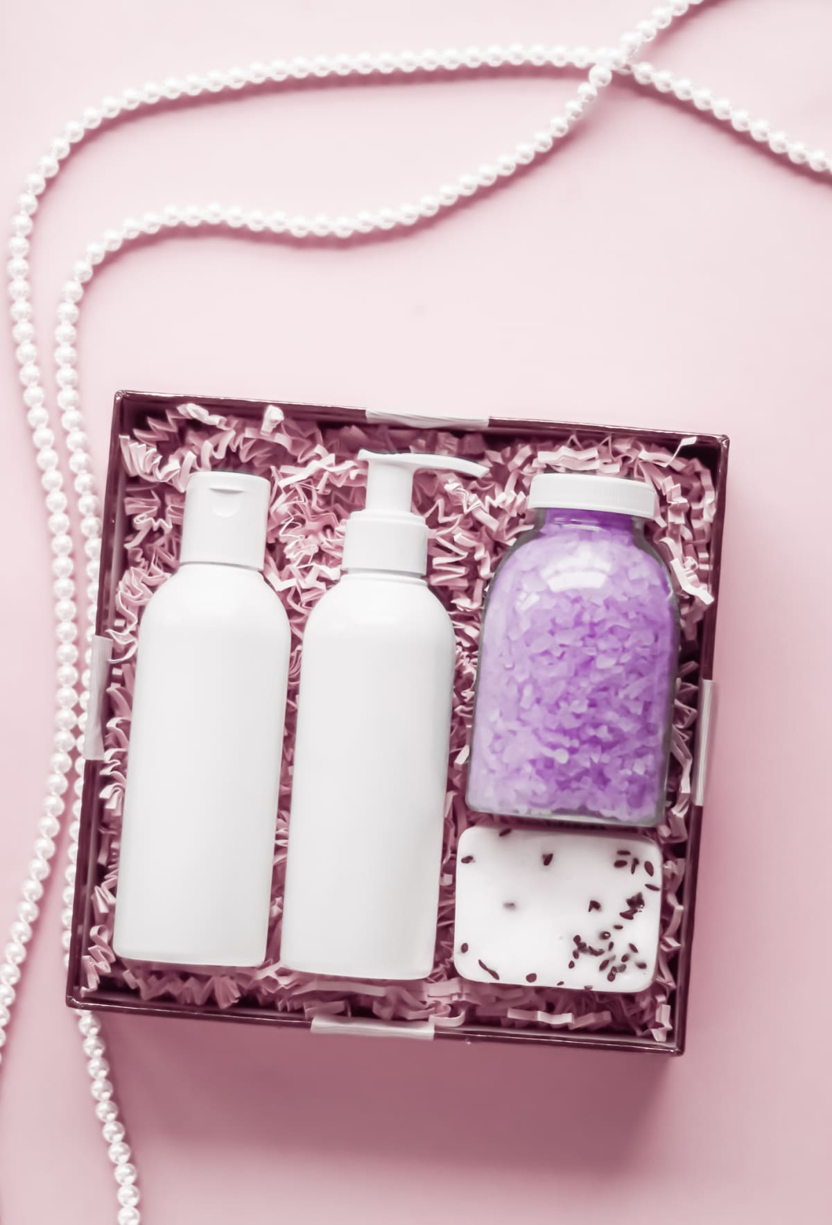 Shampoo, conditioner, soap, and bath salts in a box with pink decor