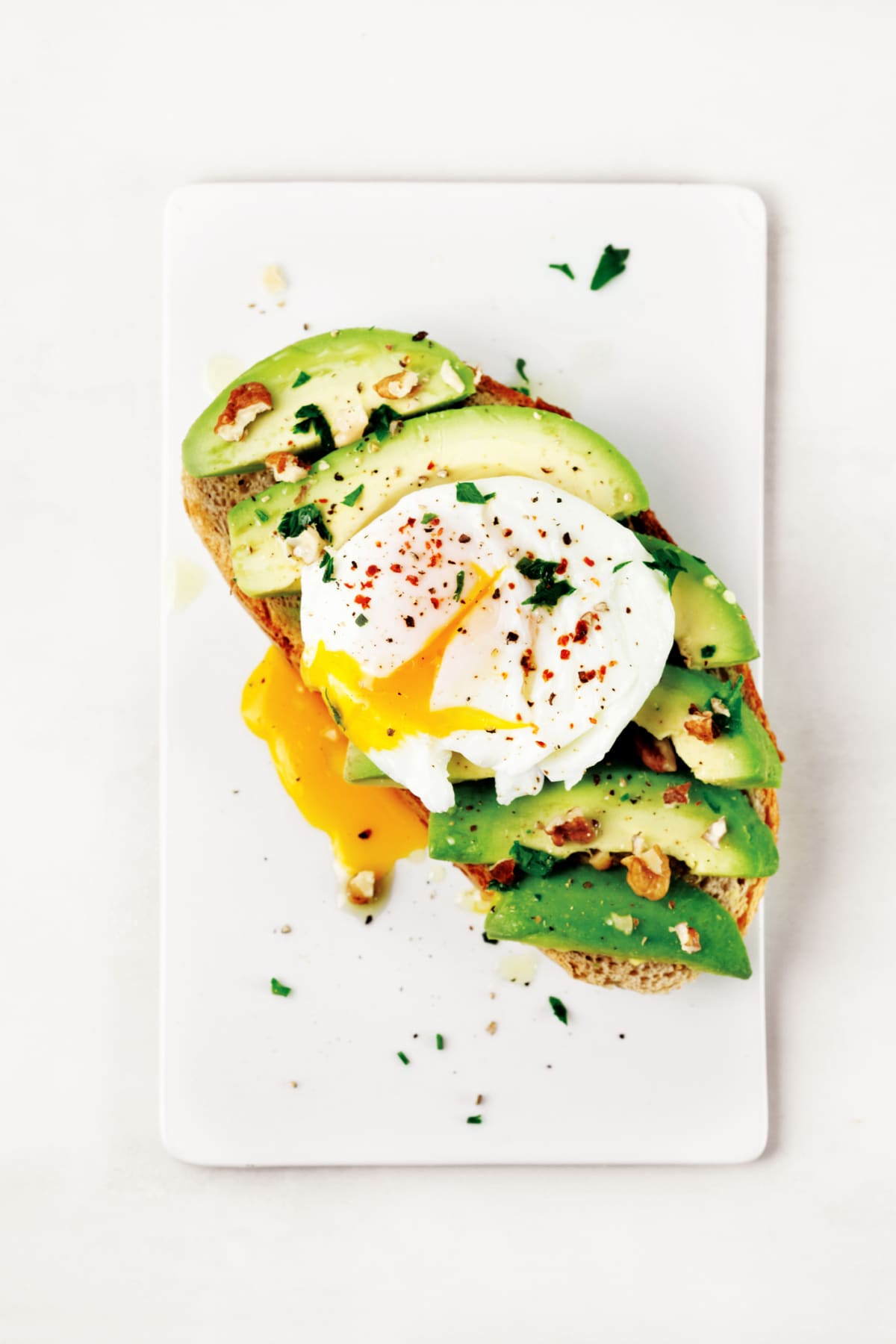 Poached egg on top of avocado toast with fresh herb and spice garnishes